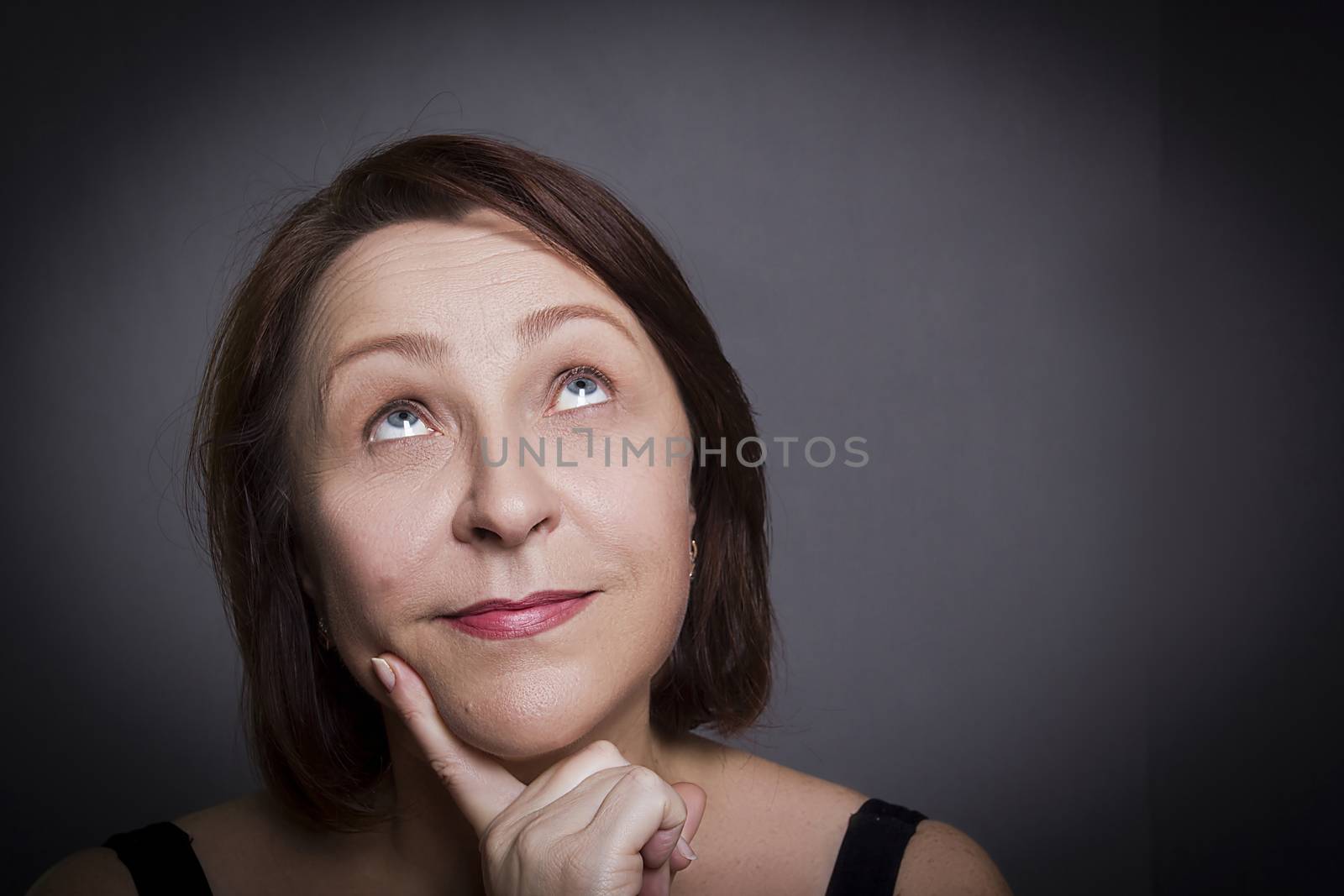 Woman grimaces in front of camera on gray background