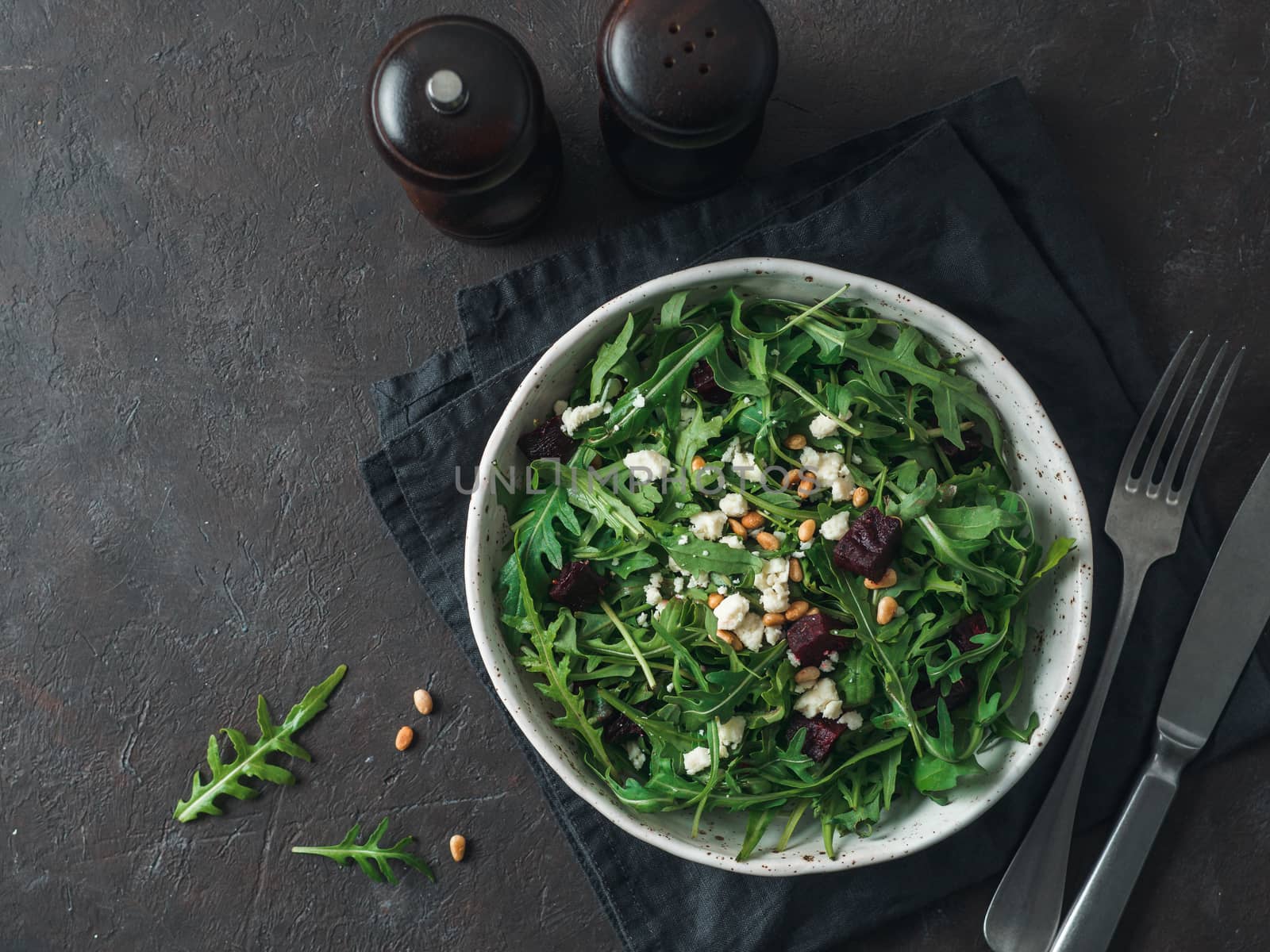 Beetroot, aragula and soft cheese salad over black background. Top view or flat lay. Copy space for text. Idea and recipe for healthy vegetarian salad. Clean eating diet concept