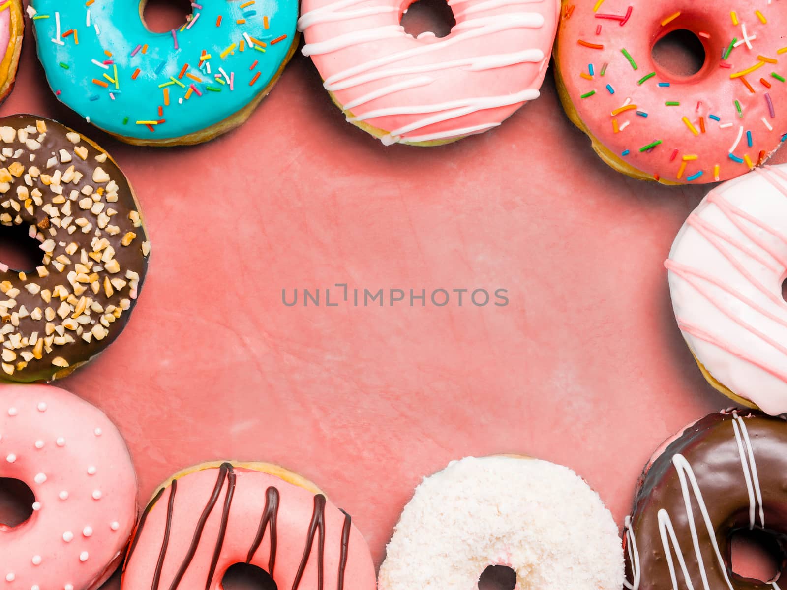 Top view of assorted donuts on blue concrete background with copy space. Colorful donuts background. Various glazed doughnuts with sprinkles.