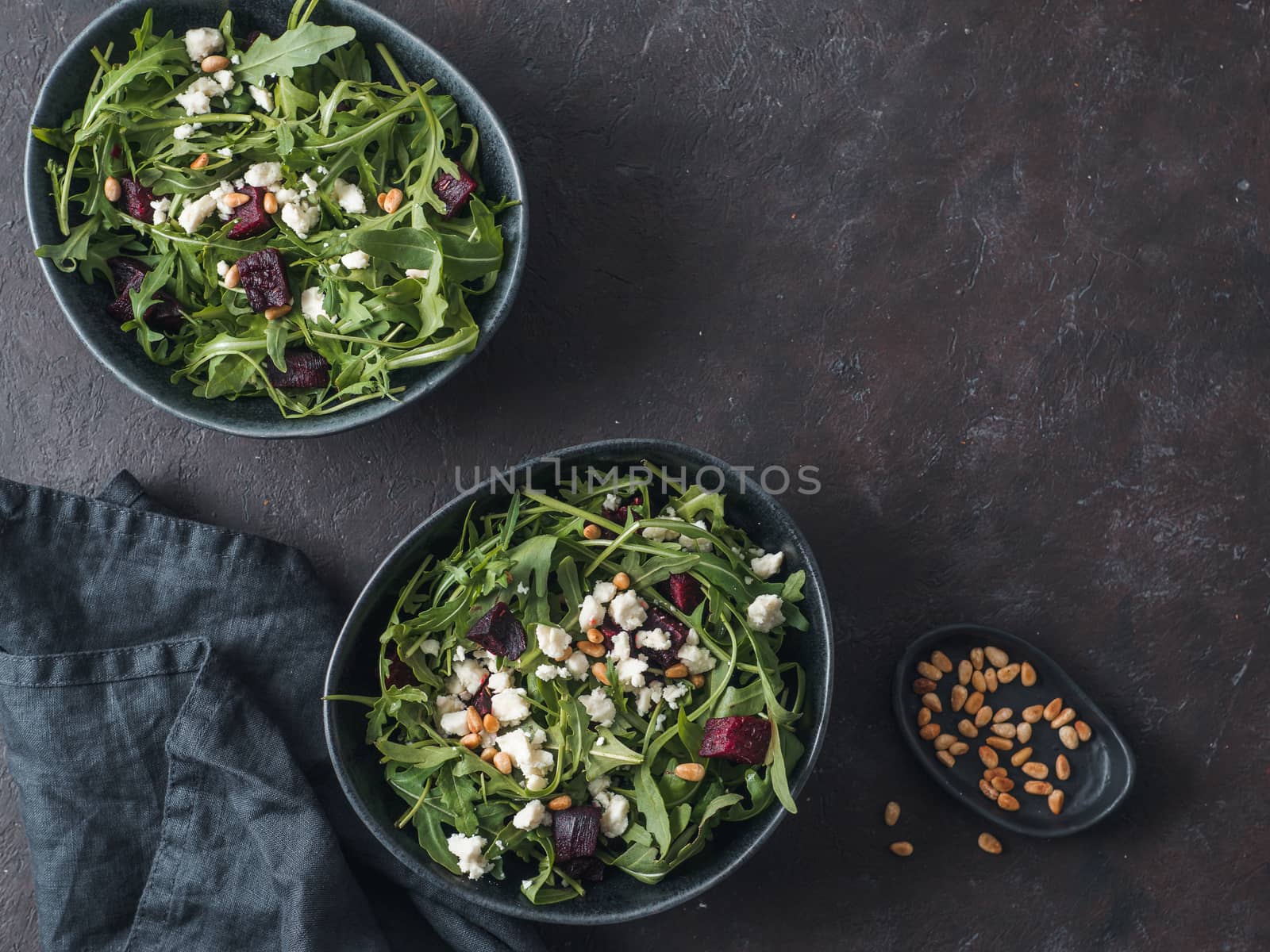 Beetroot, aragula and soft cheese salad over black background. Top view or flat lay. Copy space for text. Idea and recipe for healthy vegetarian salad. Clean eating diet concept