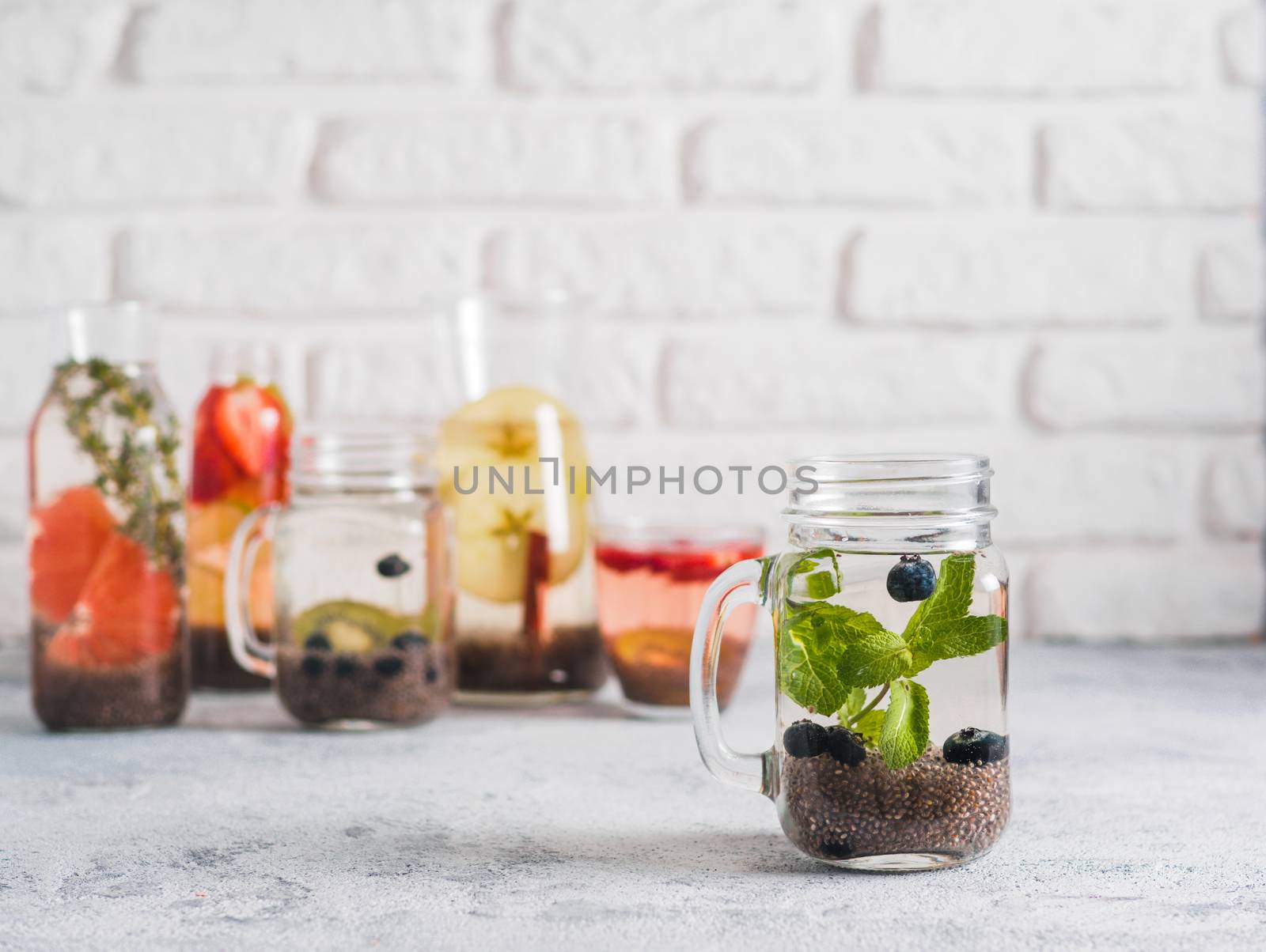 Chia water in mason jar with mint and blueberry on gray cement background. Chia infused detox water with berries, fruits and herbs. Copy space for text. Healthy eating, drinks, diet, detox concept