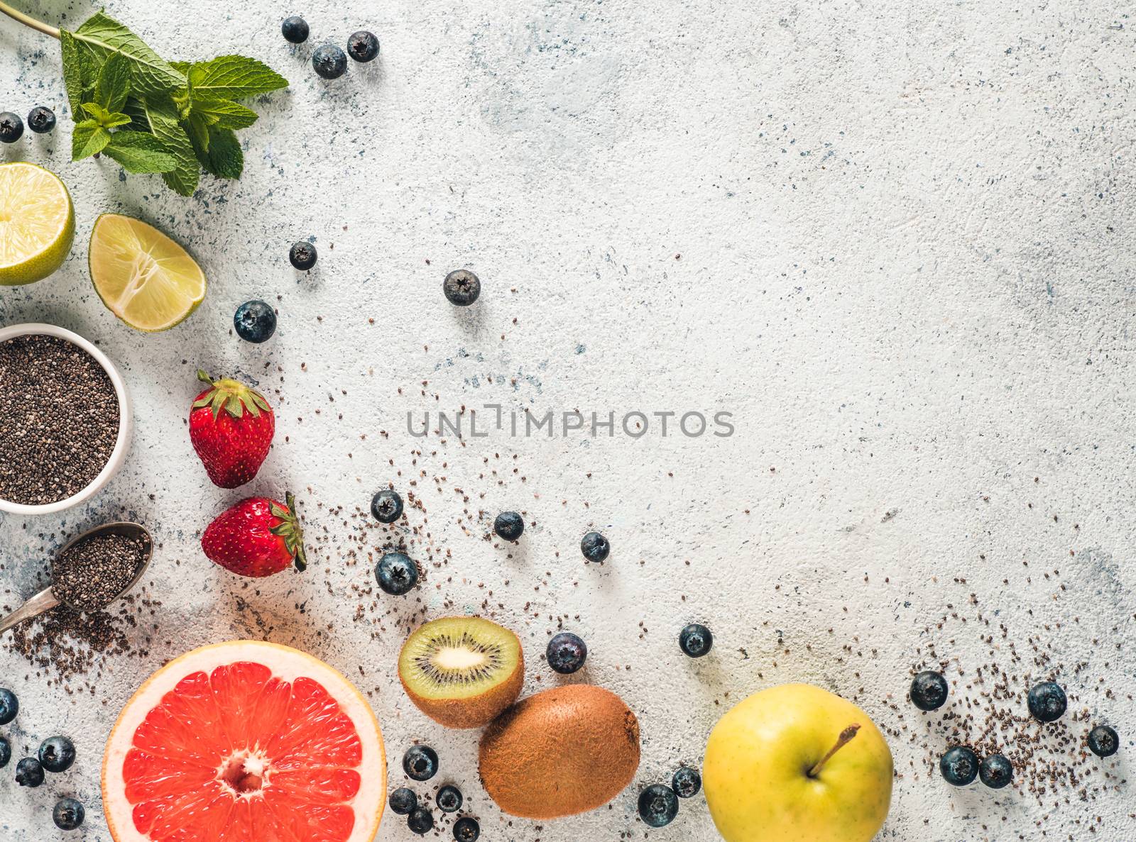 Ingredients for chia water and infused detox drink on gray concrete background. Copy space. Above view, copy space. Fresh fruits, berries, chia seeds and mint. Healthy food, detox, diet, vegan concept
