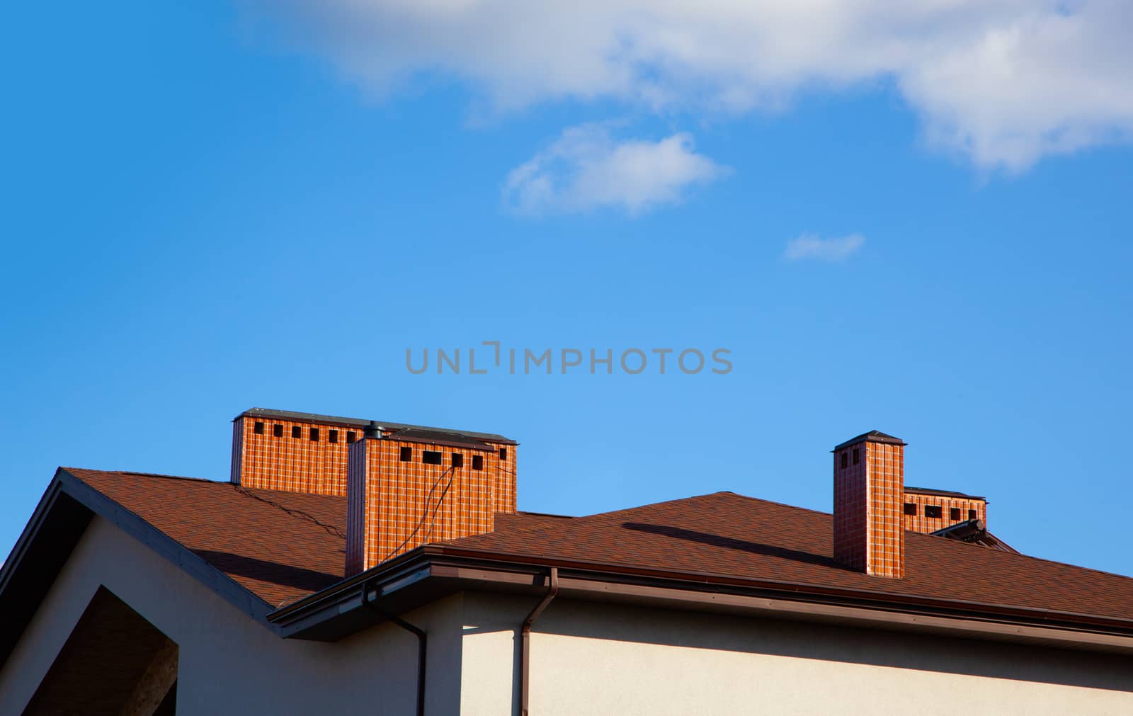 House with brick chimney in bright sunlight, against a deep blue sky