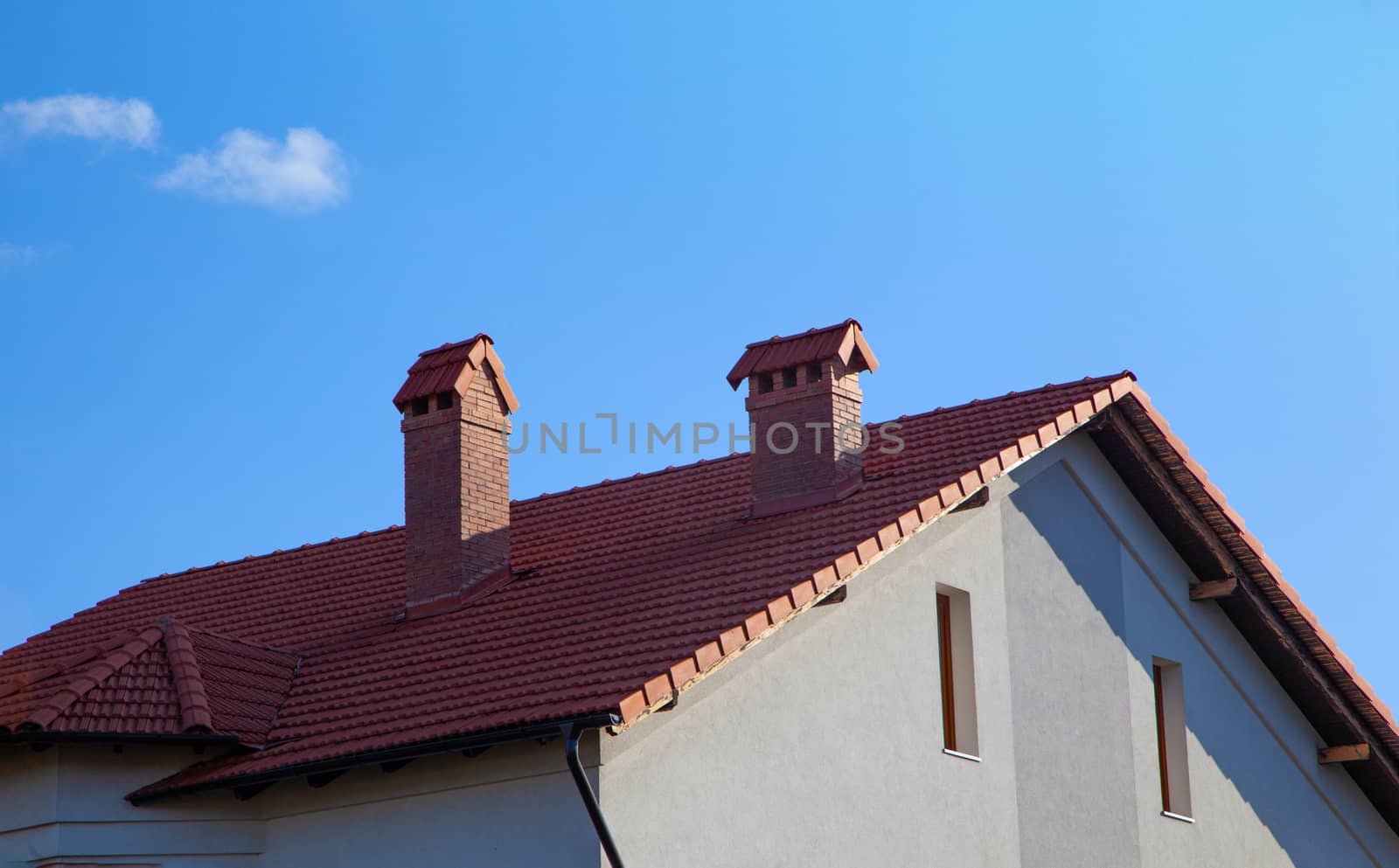 House with brick chimney in bright sunlight, against a deep blue sky