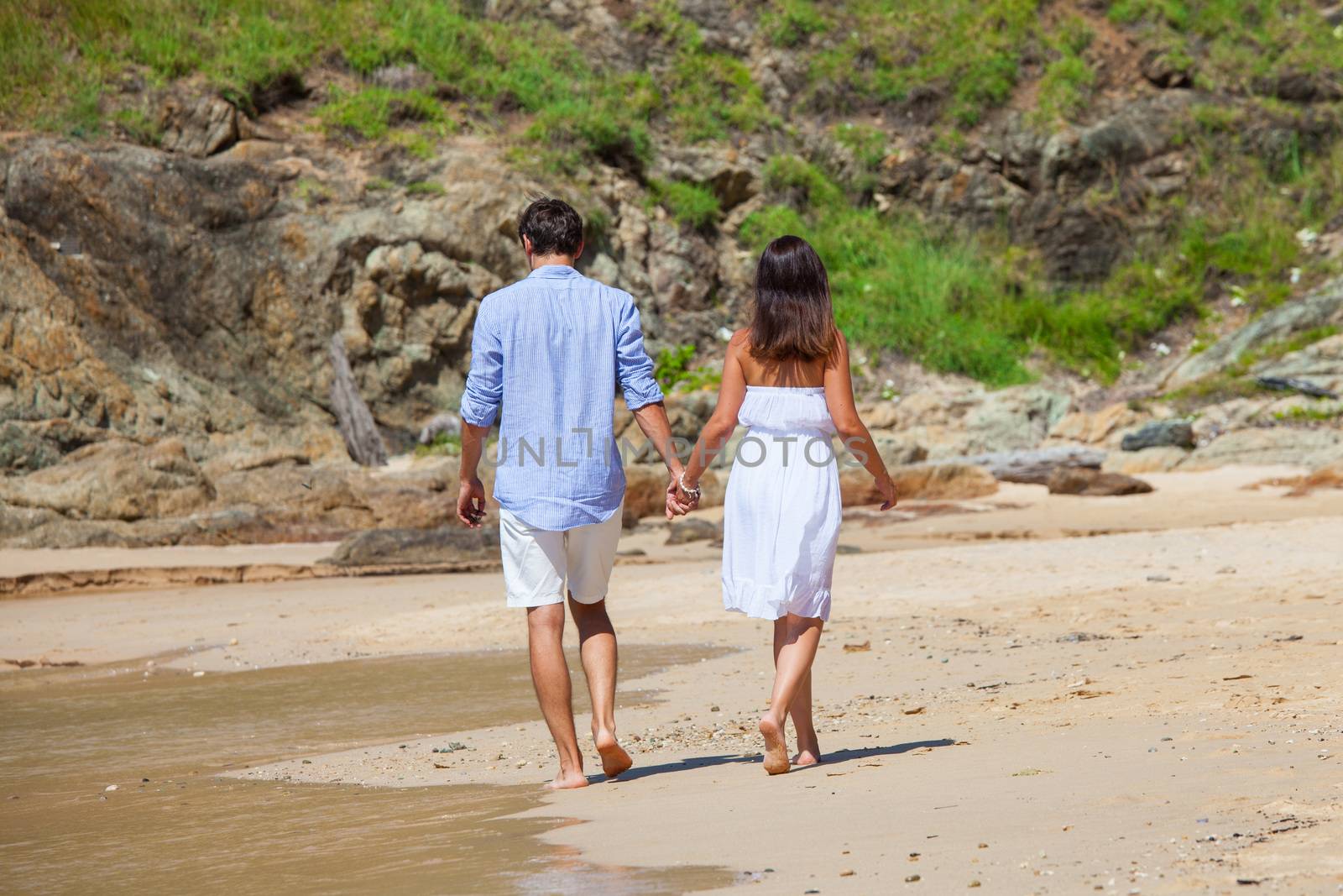 Couple walking on sand of tropical beach