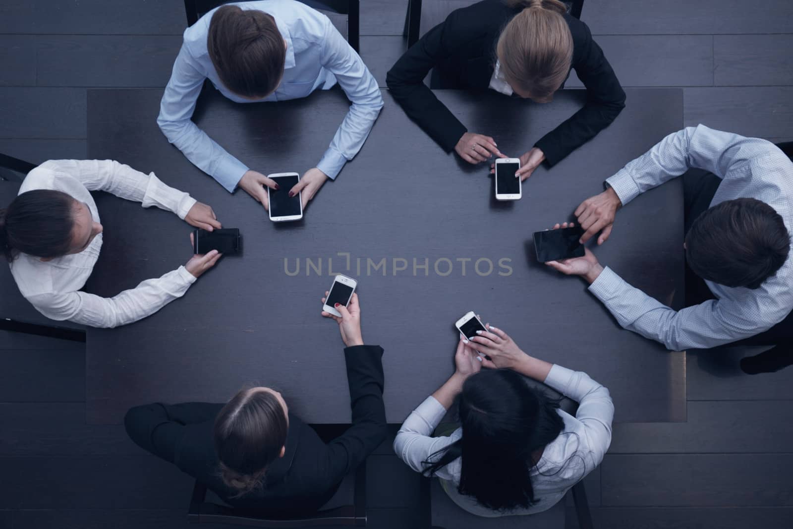 Business people with smartphones sitting around the table, top view