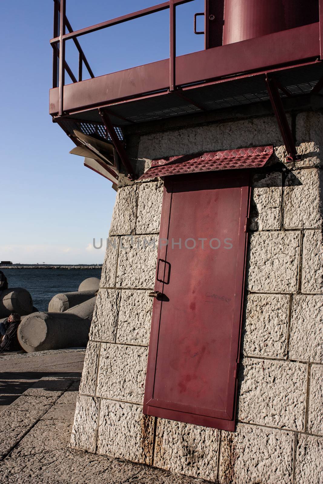Red painted iron door belonging to the lighthouse in the dam of Sottomarina in Veneto Italy.