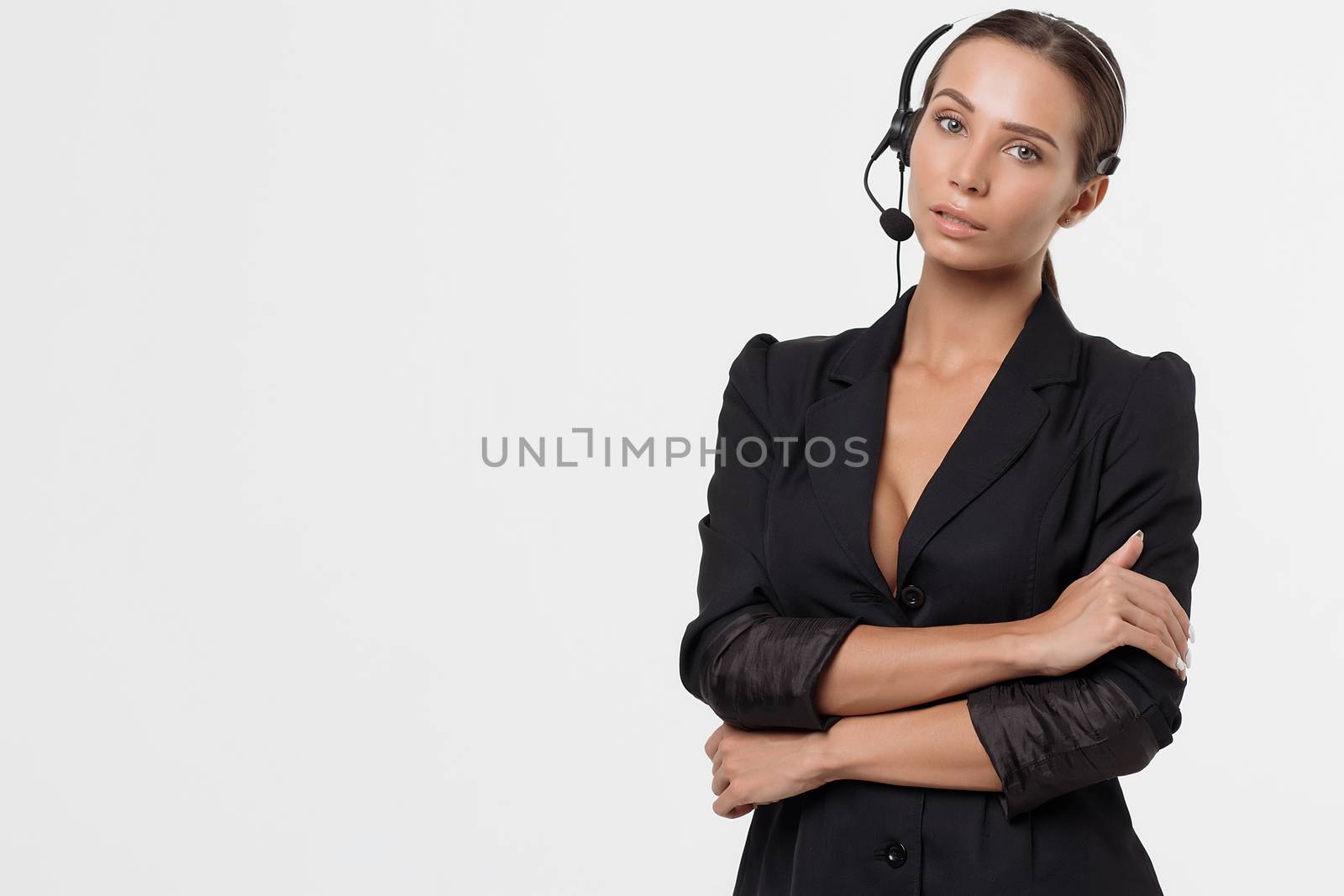 Isolated attractive sexy woman in black opened costume with hand on belt holding headphone's micro and looking away