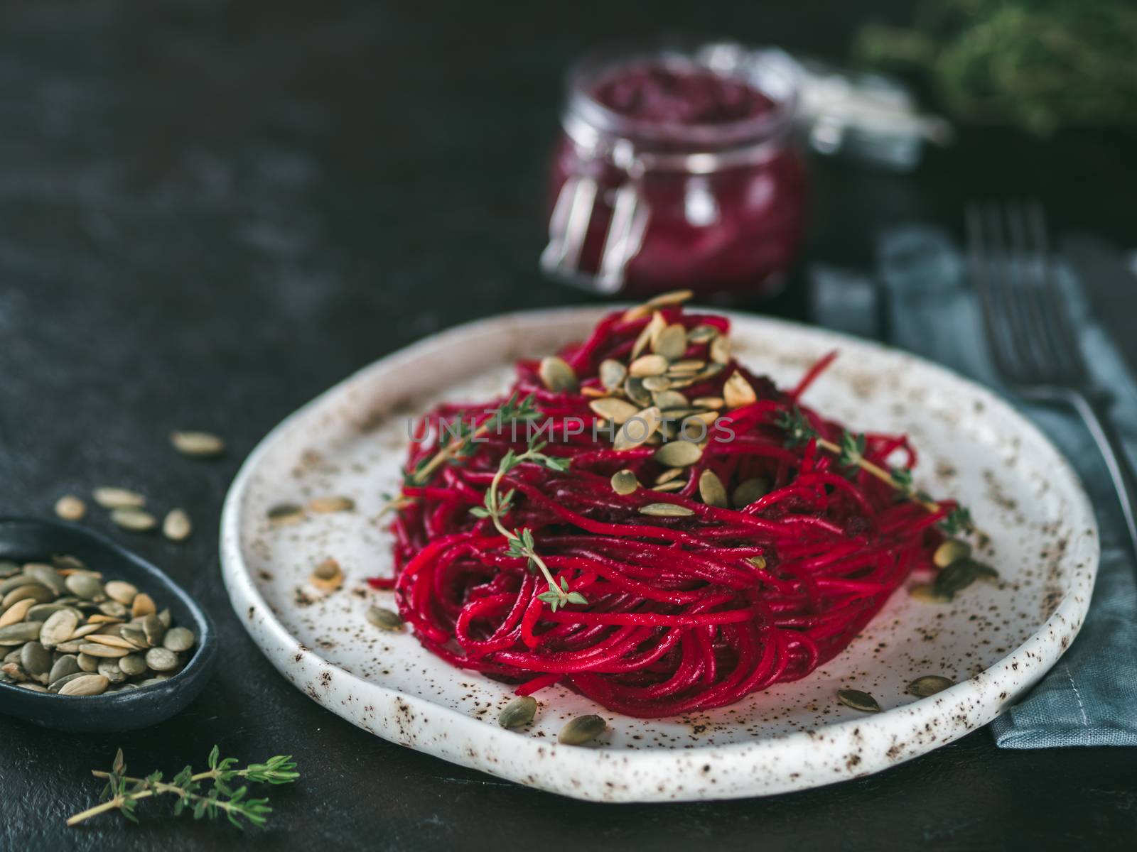 Beetroot pesto or hummus. Homemade beet pesto sauce in glass jar and fresh thyme on dark black background. Copy space for text. Ideas and recipes for healthy vegetarian detox diet food