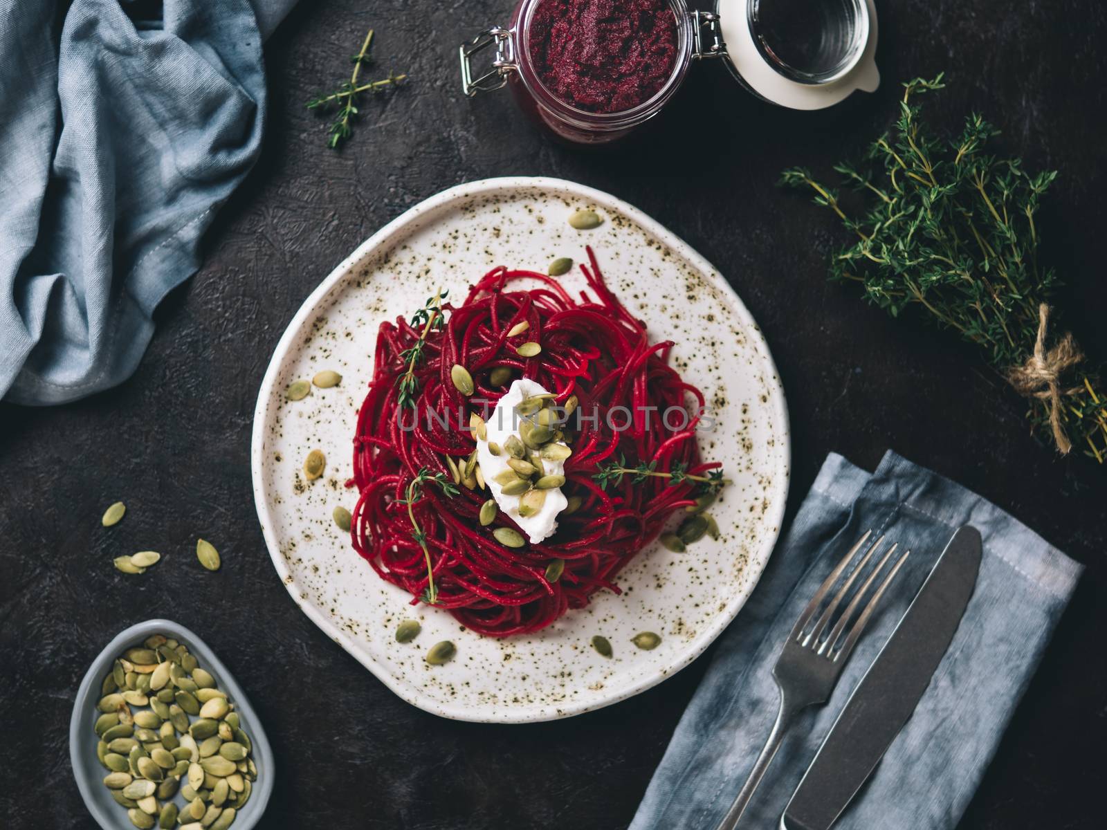 Beetroot pesto or hummus. Homemade beet pesto sauce in glass jar and fresh thyme on dark black background. Copy space for text. Ideas and recipes for healthy vegetarian detox diet food