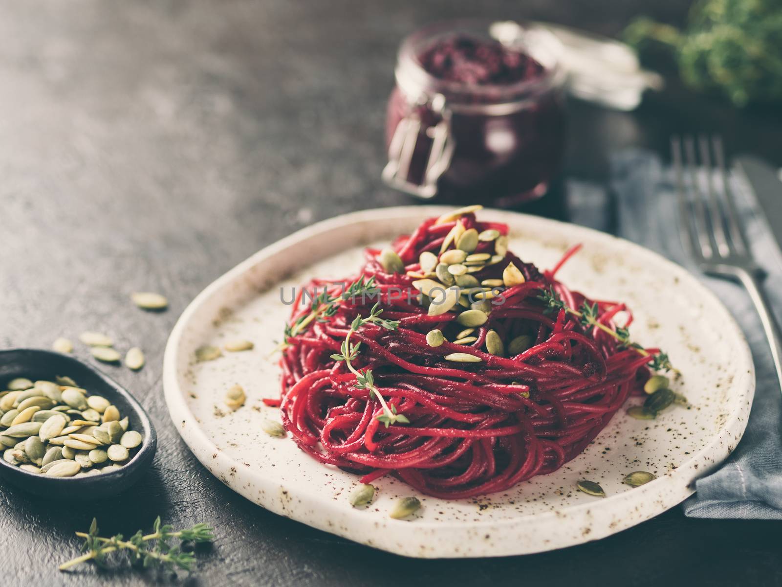 Beetroot pesto or hummus. Homemade beet pesto sauce in glass jar and fresh thyme on dark black background. Copy space for text. Ideas and recipes for healthy vegetarian detox diet food