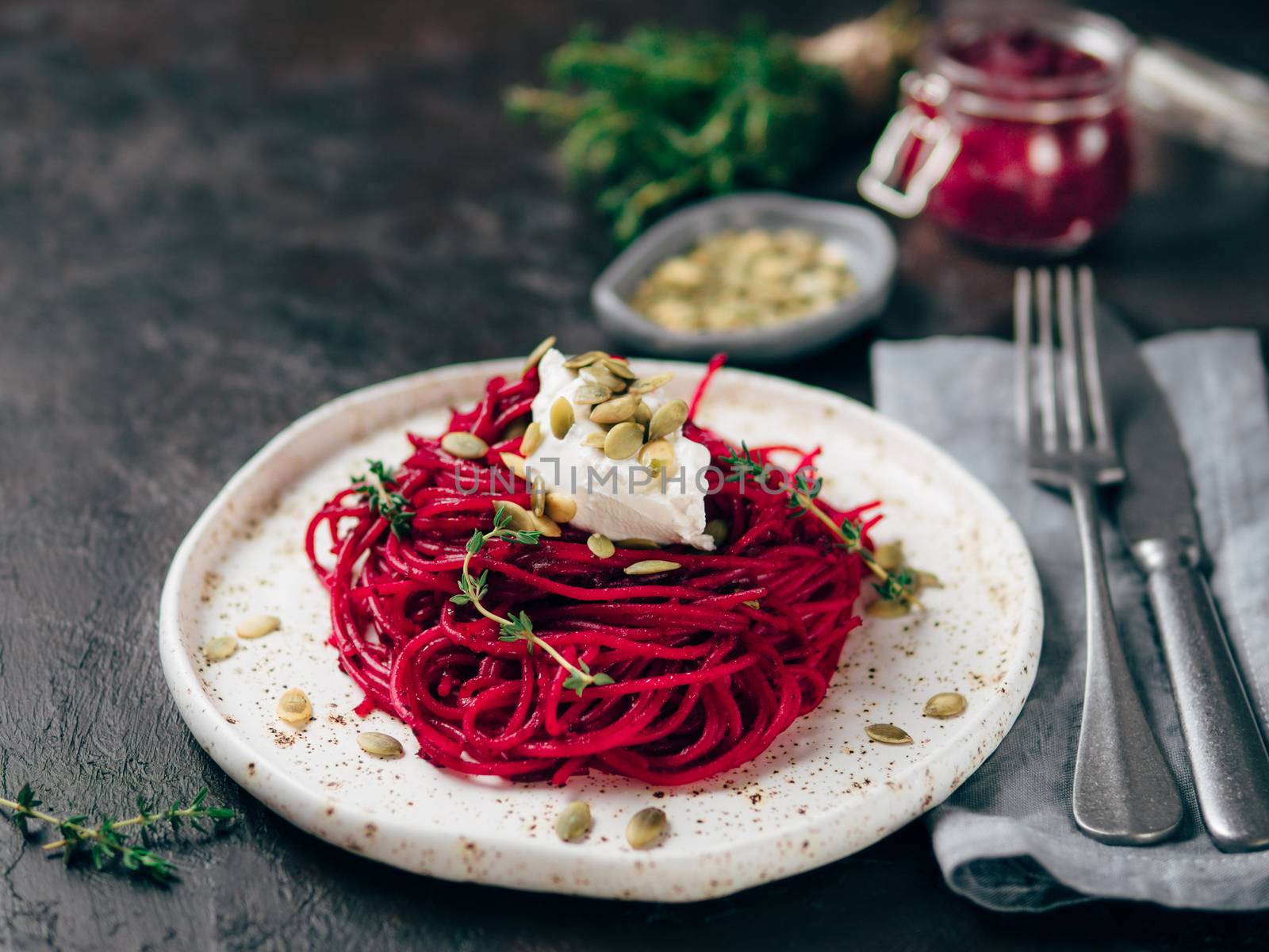 Beetroot pesto or hummus. Homemade beet pesto sauce in glass jar and fresh thyme on dark black background. Copy space for text. Ideas and recipes for healthy vegetarian detox diet food