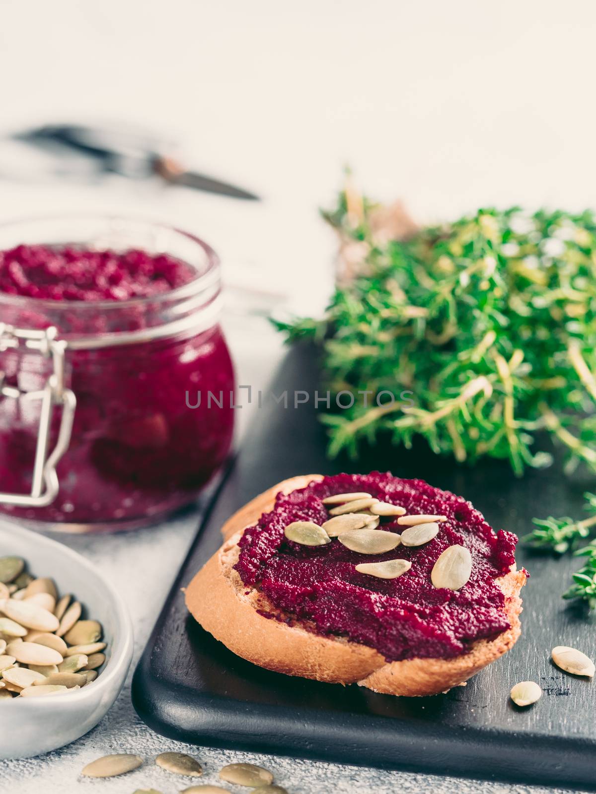 Beetroot pesto or hummus. Homemade beet pesto sauce in glass jar and fresh thyme on dark black background. Copy space for text. Ideas and recipes for healthy vegetarian detox diet food