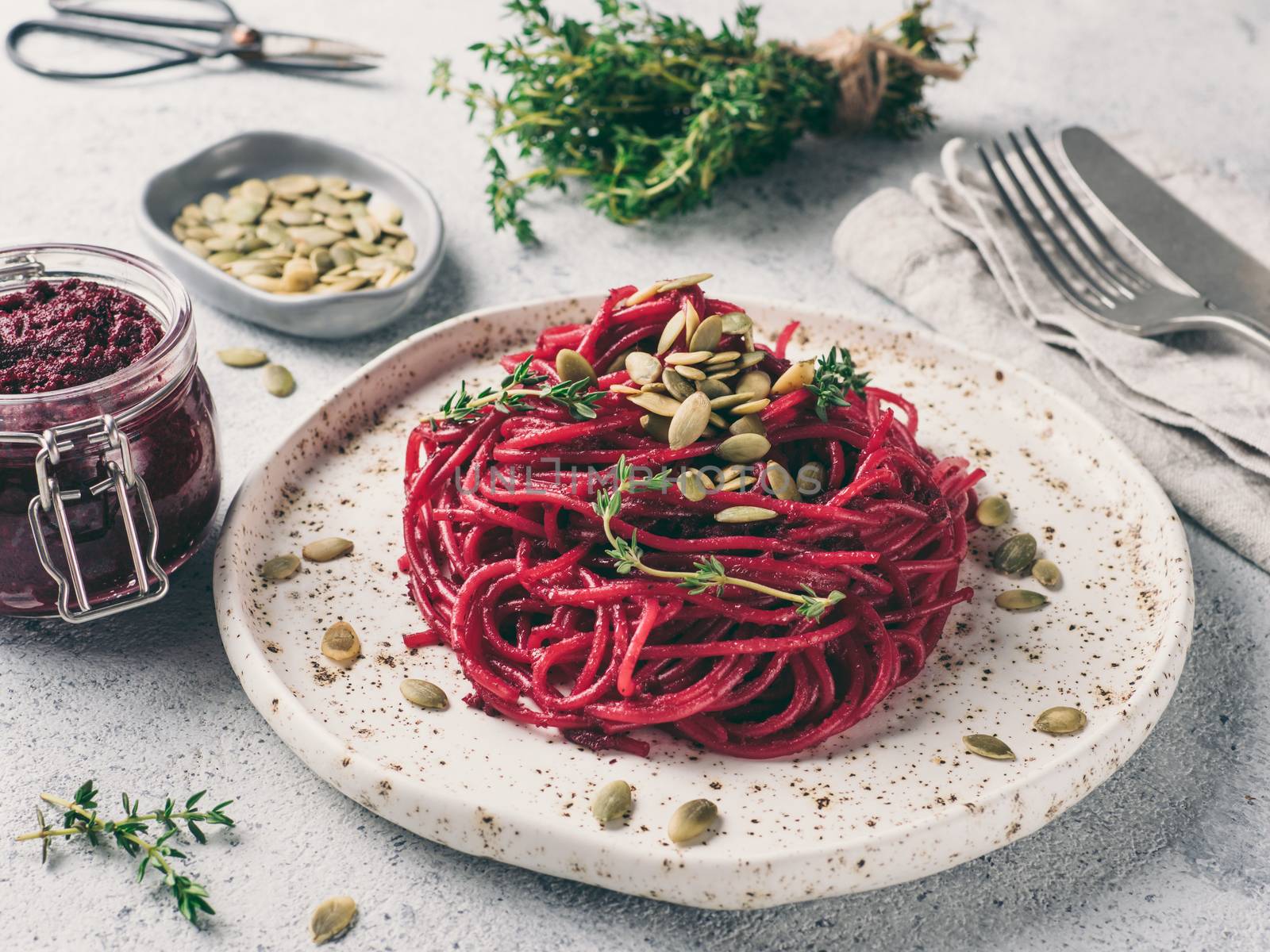 Beetroot pesto or hummus. Homemade beet pesto sauce in glass jar and fresh thyme on dark black background. Copy space for text. Ideas and recipes for healthy vegetarian detox diet food