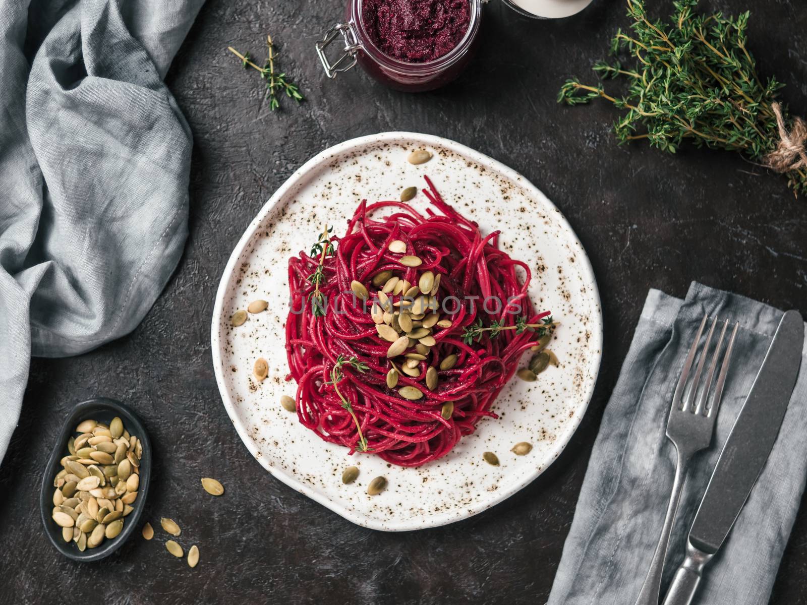 Beetroot pesto or hummus. Homemade beet pesto sauce in glass jar and fresh thyme on dark black background. Copy space for text. Ideas and recipes for healthy vegetarian detox diet food