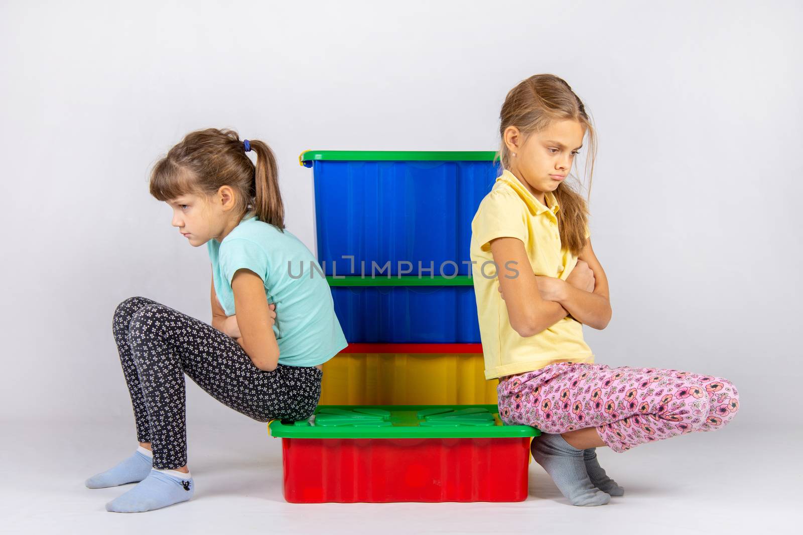 Two girls quarreled, sit on a box and turned away from each other