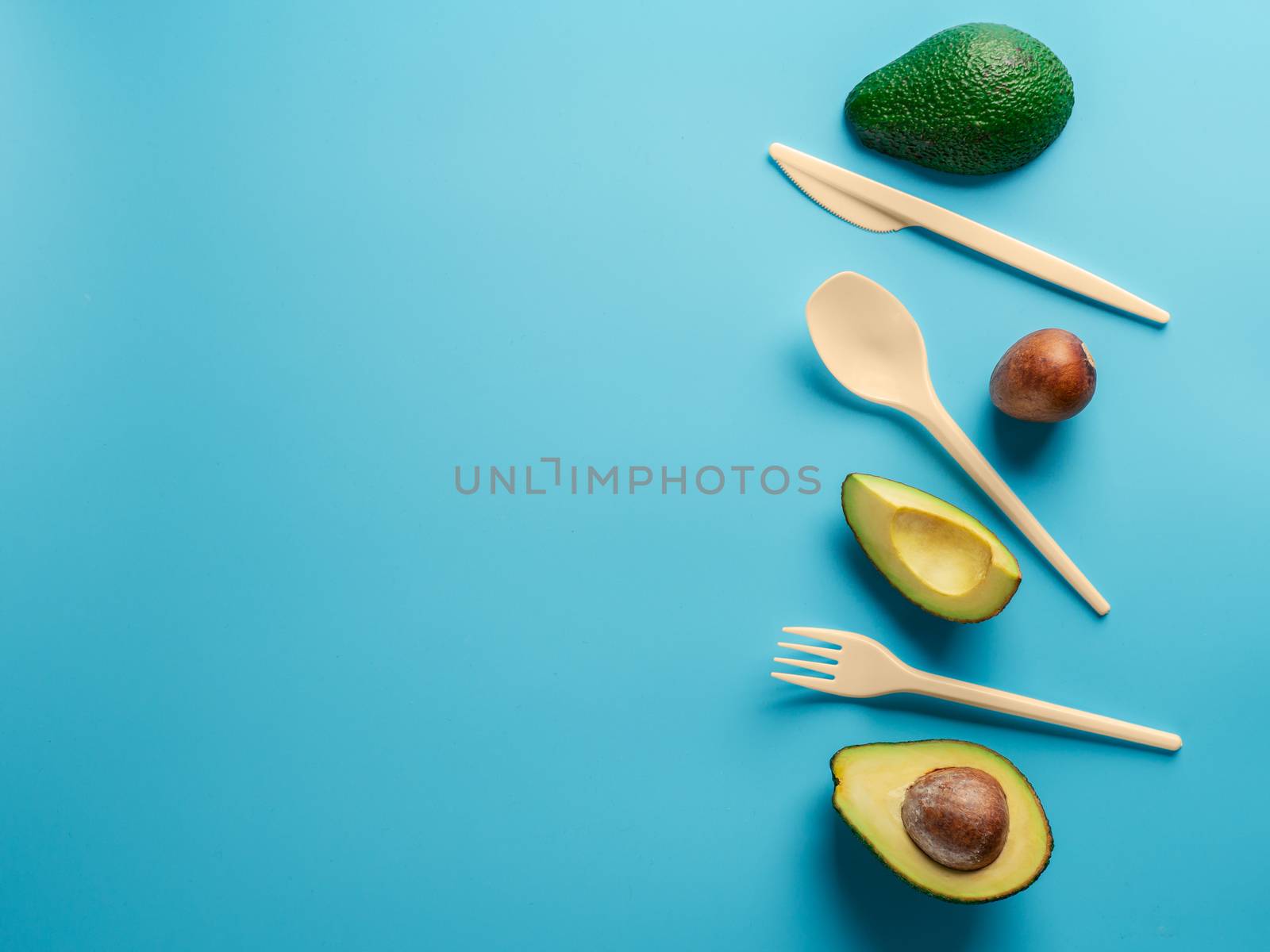 Avocado Seeds Biodegradable Single-Use Cutlery. Bioplastic - Great alternative to plastic disposable cutlery. Minimal concept on blue background. Copy space for text or design