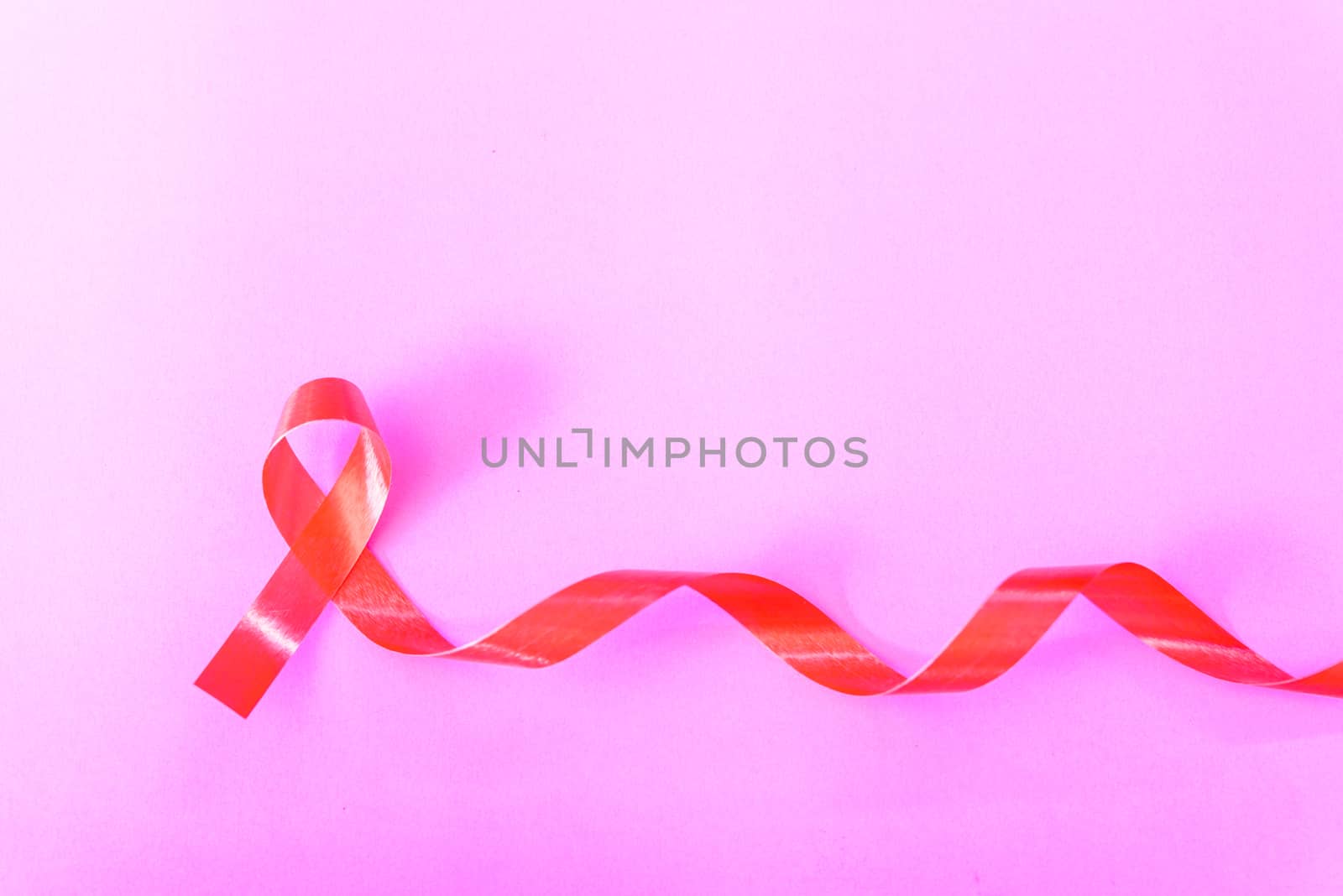 Red Ribbon Support HIV, AIDS on pink background and copy space for use