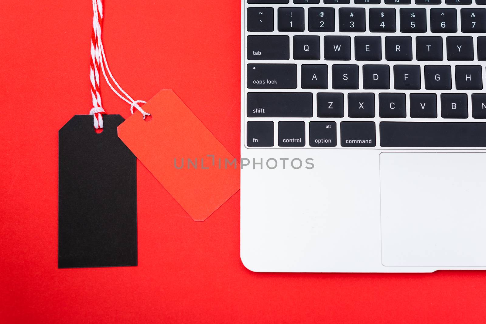 Internet online shopping marketing, top view of workspace with Blank red and black tags near laptop computer on red background
