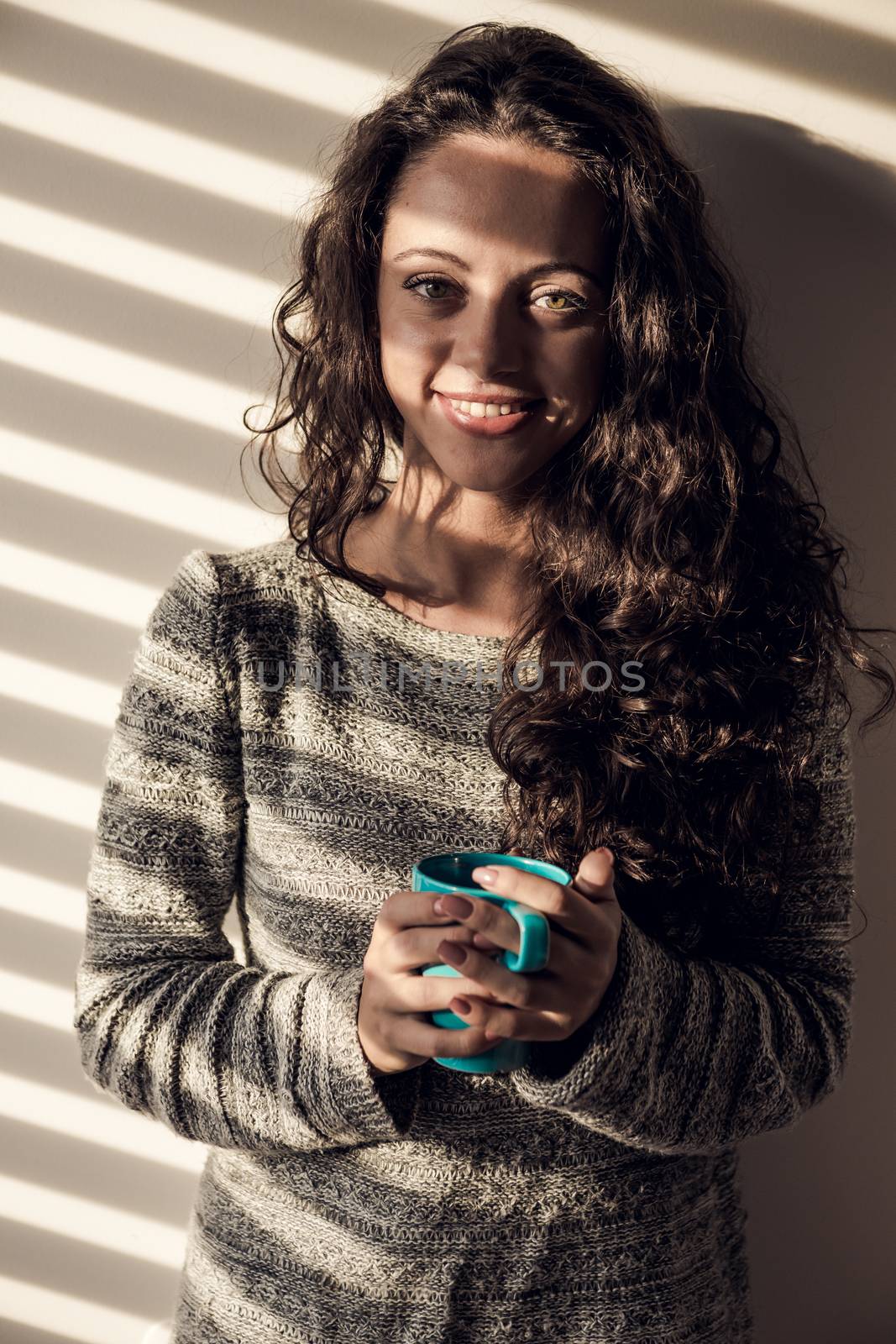 Portrait of a beautiful woman on her bedroom drinking coffee