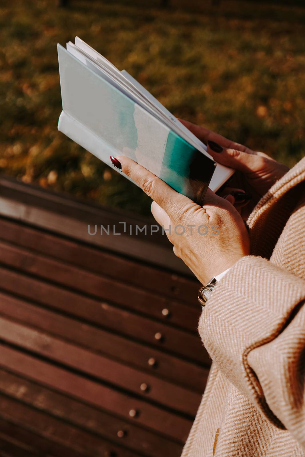 Woman in an autumn coat holds a book. Autumn park by natali_brill