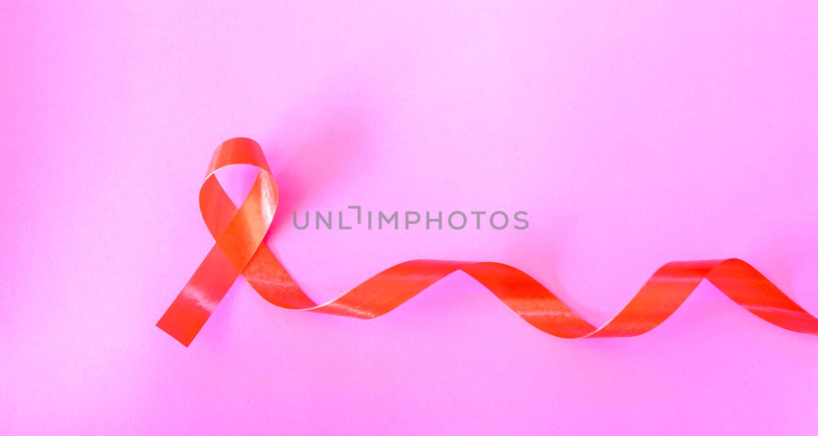 Red Ribbon Support HIV, AIDS on pink background and copy space for use