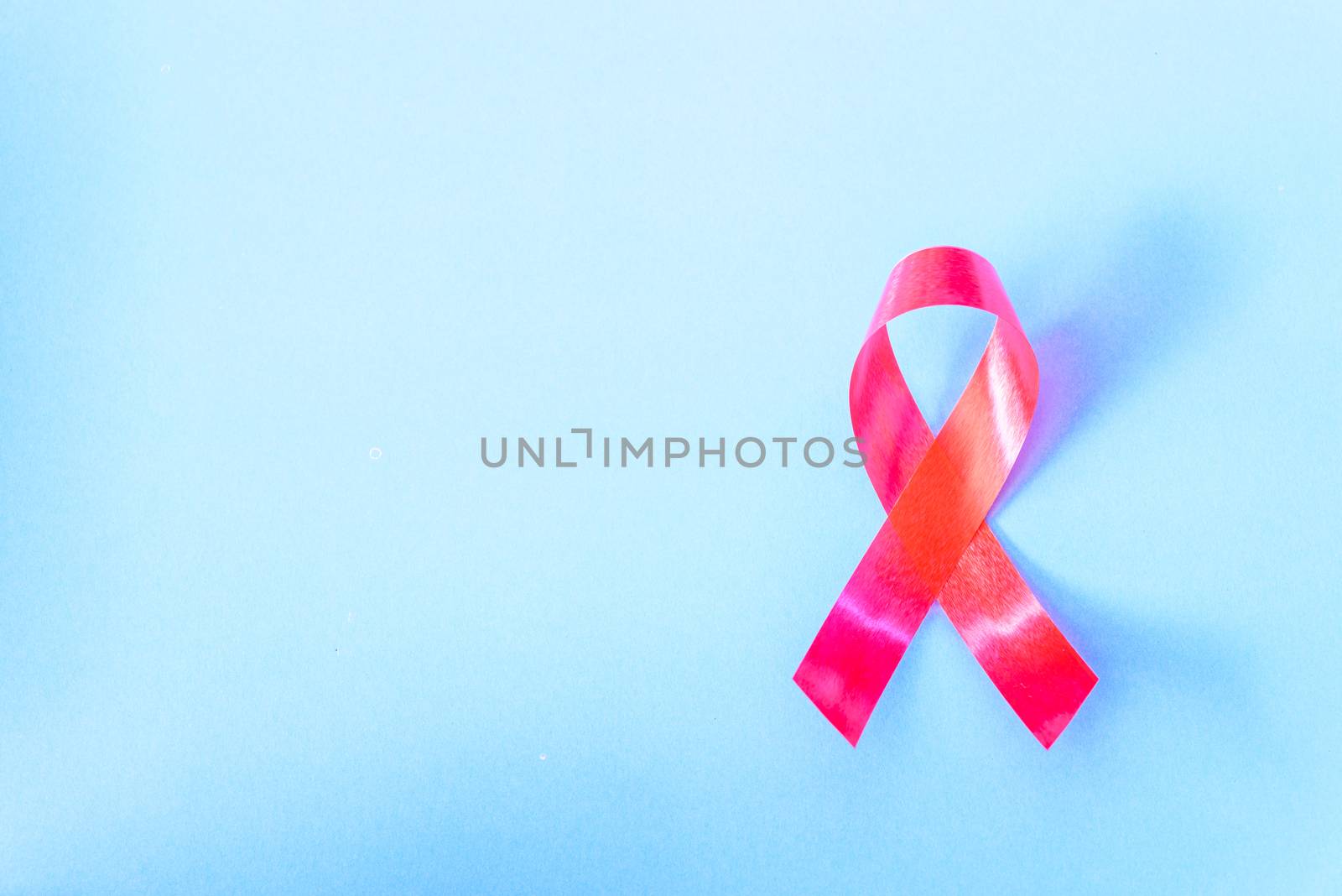 Red Ribbon Support HIV, AIDS on blue background and copy space for use