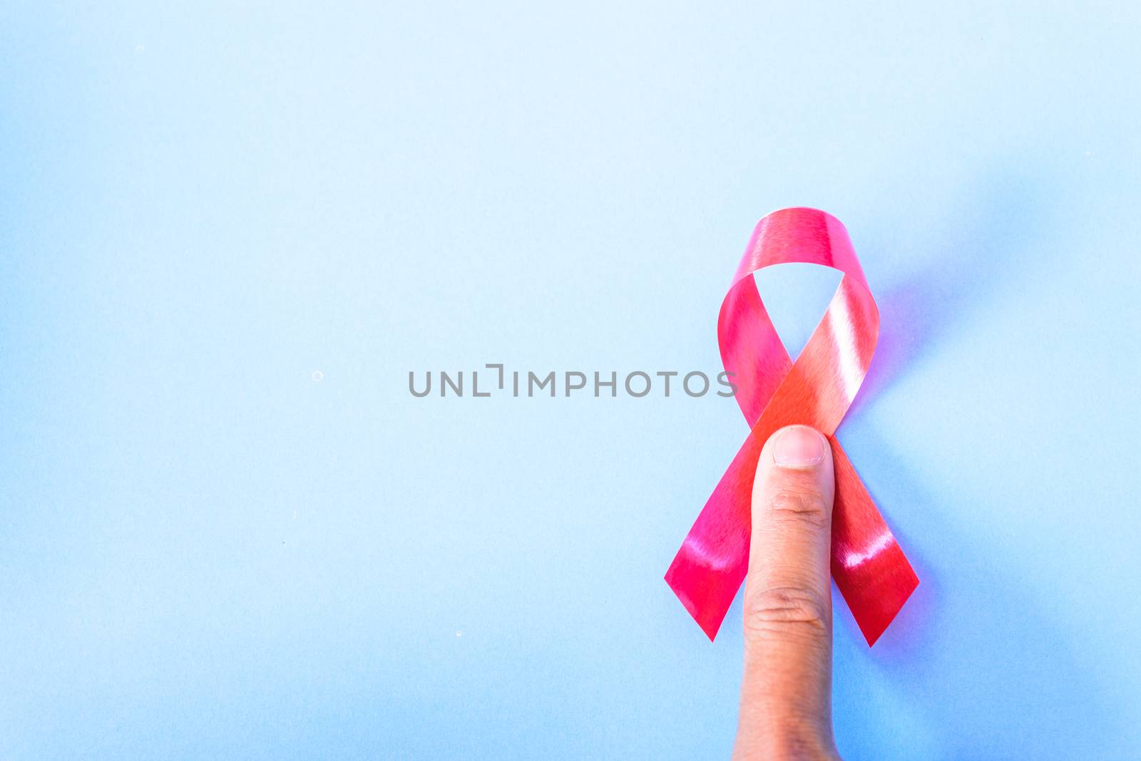 Red Ribbon Support HIV, AIDS and have finger point on blue background and copy space for use