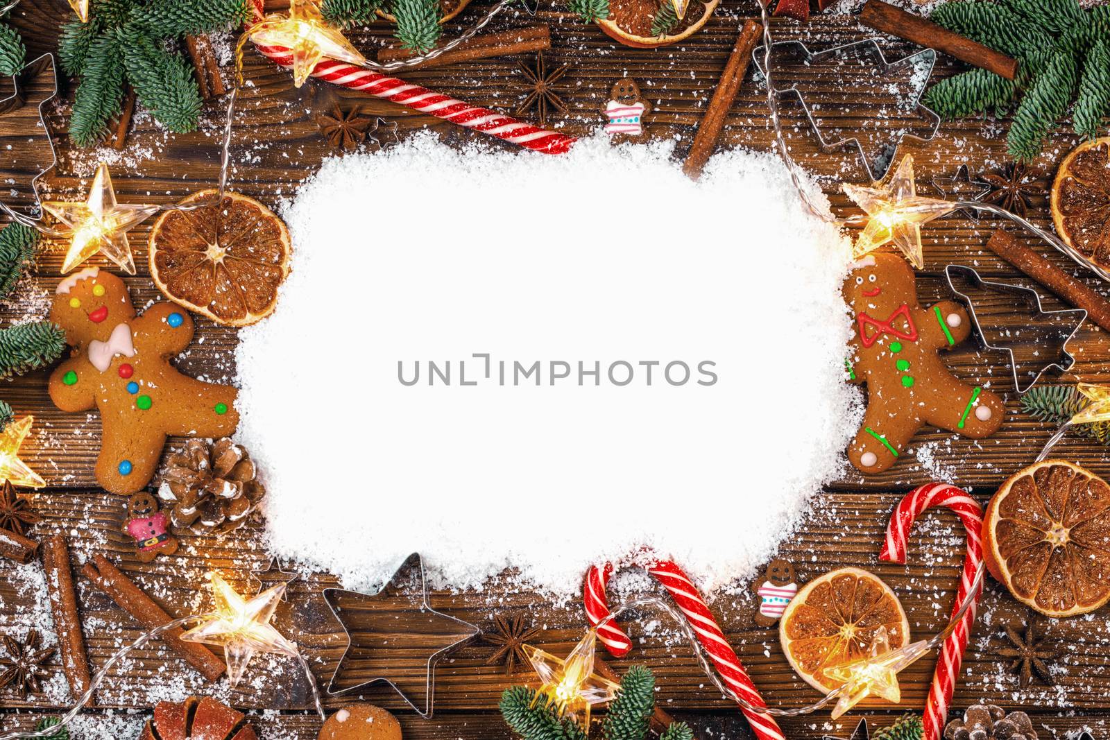 Christmas food frame. Gingerbread cookies, spices and decorations on wooden background with white copy space on snow