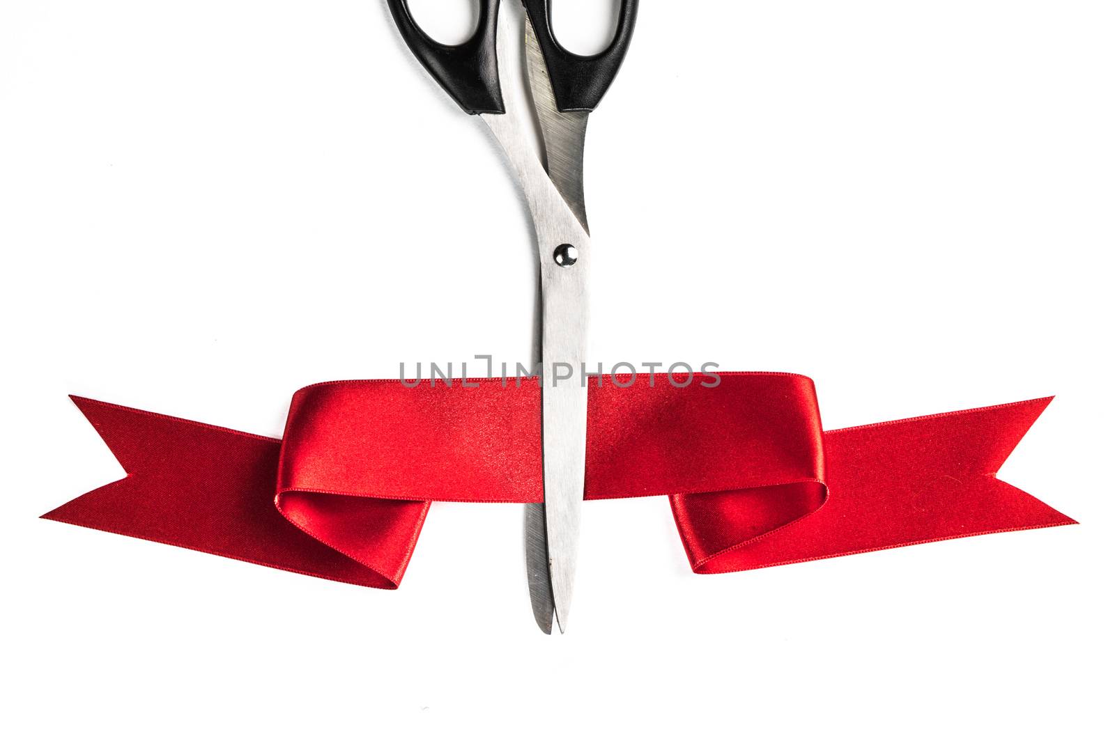 Scissors cutting through red ribbon or tape, isolated on white background