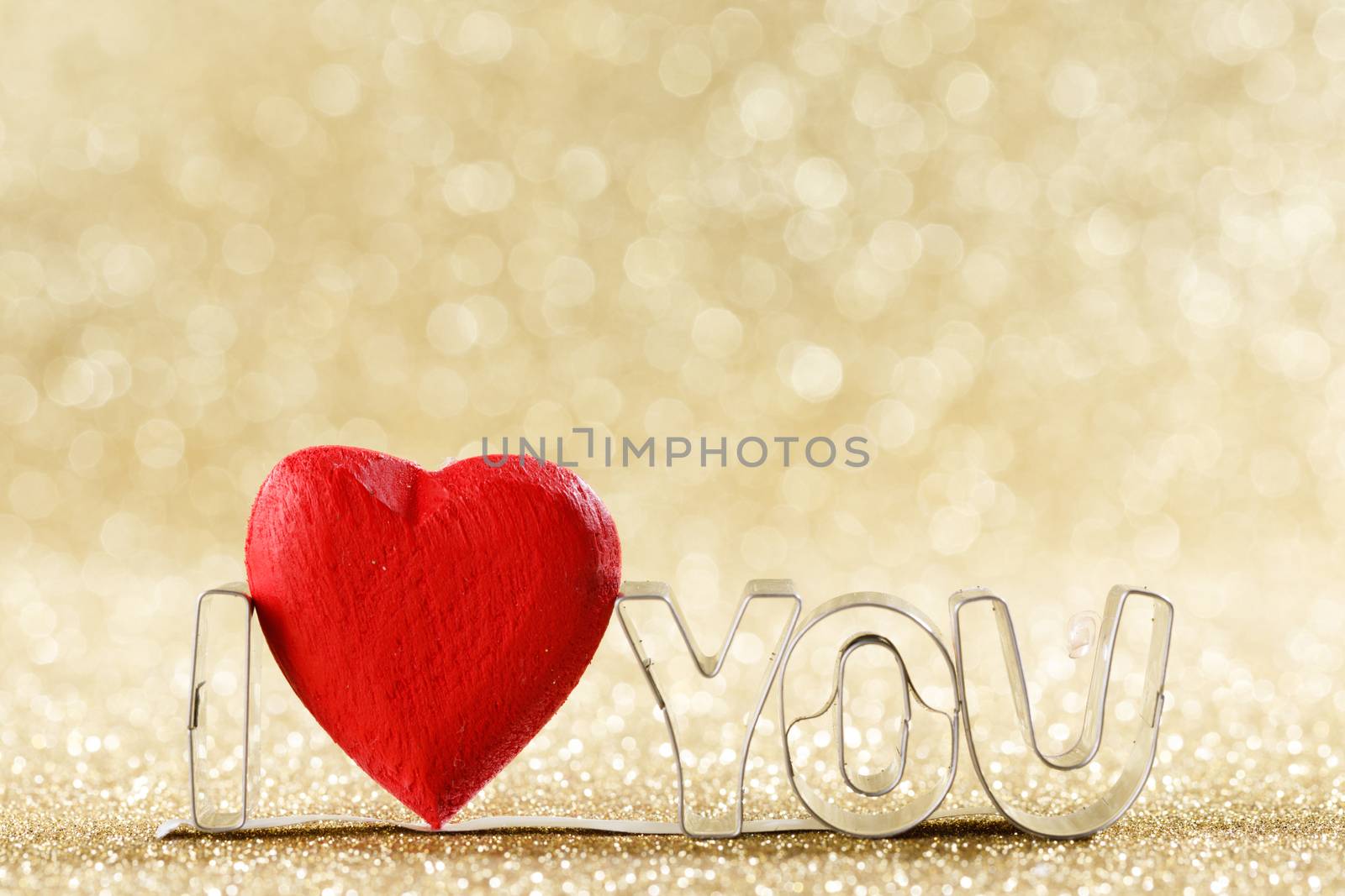 Red handmade wooden heart and words I love you on golden bright glitter lights bokeh background