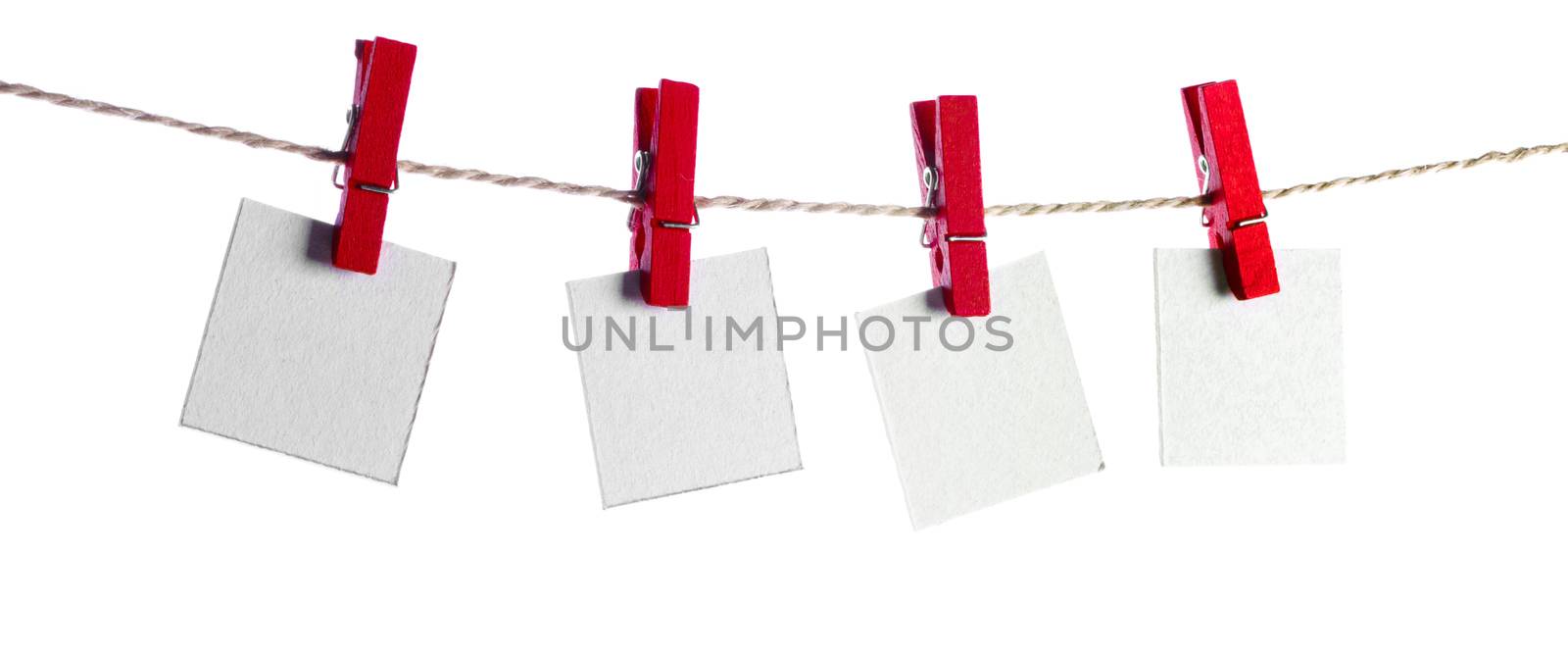 Set of four blank paper notes held on a string with clothespins isolated on white background