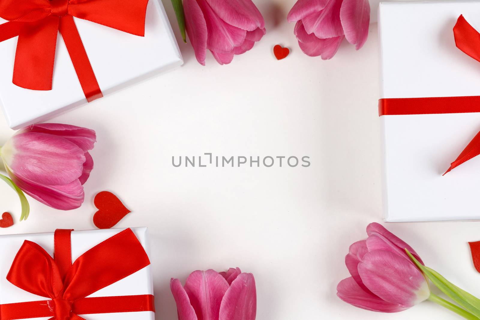 Pink tulips gifts and hearts border frame with copy space on white background Valentines day concept