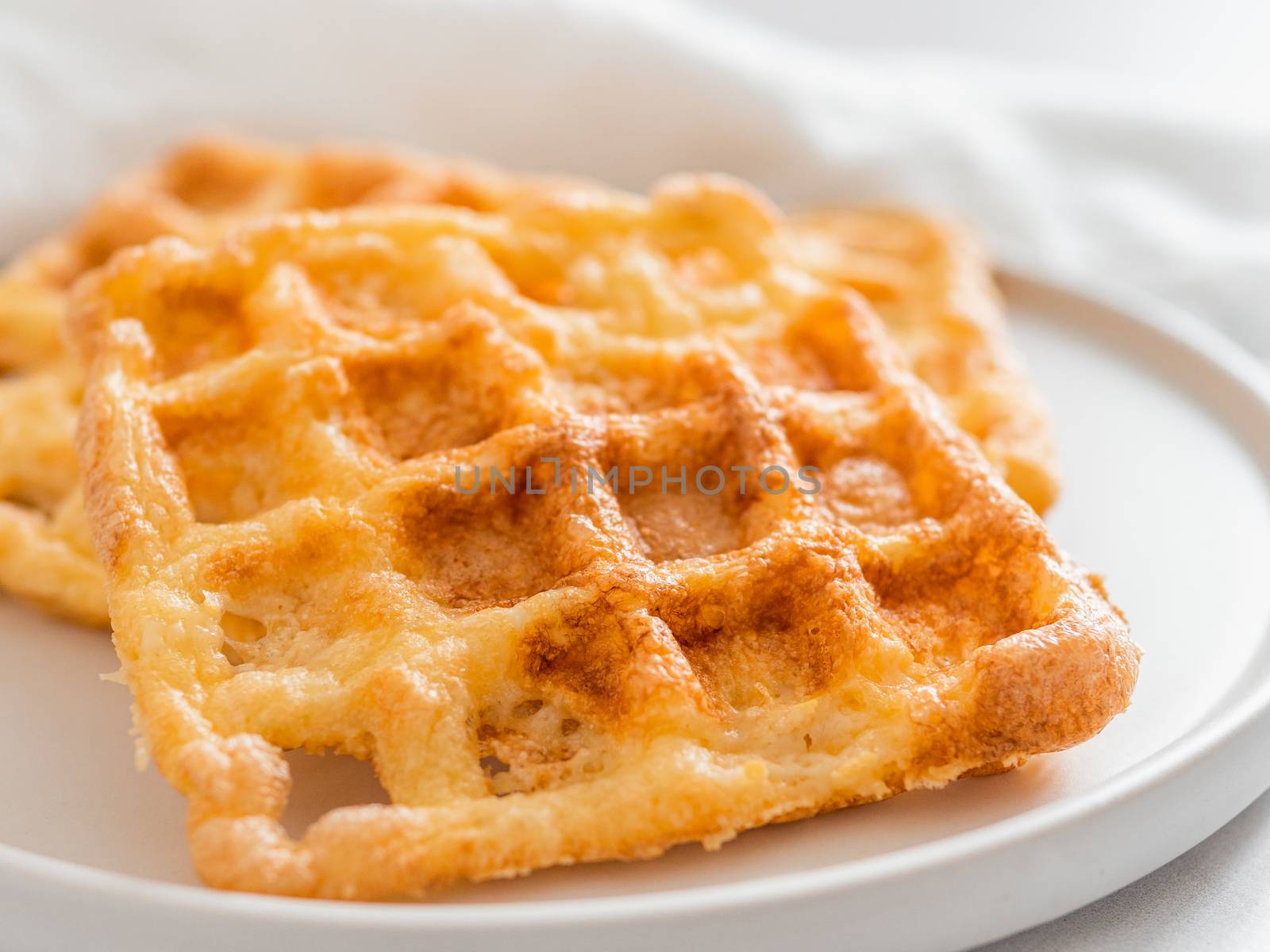 Perfect savory keto waffles. Two ingredients chaffles on plate over white marble background. Eggs and parmesan cheese low carb waffles. Extreme close up view.