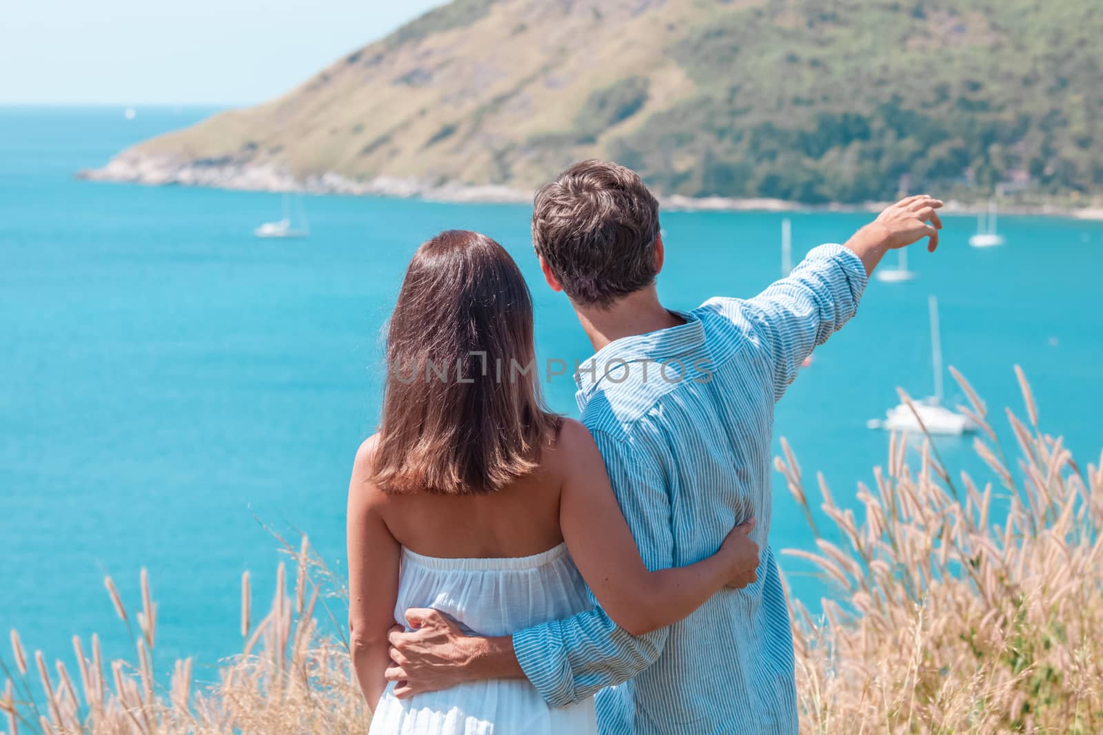 Love, travel, tourism and people concept - couple on vacation standing on mountain, hugging and pointing finger