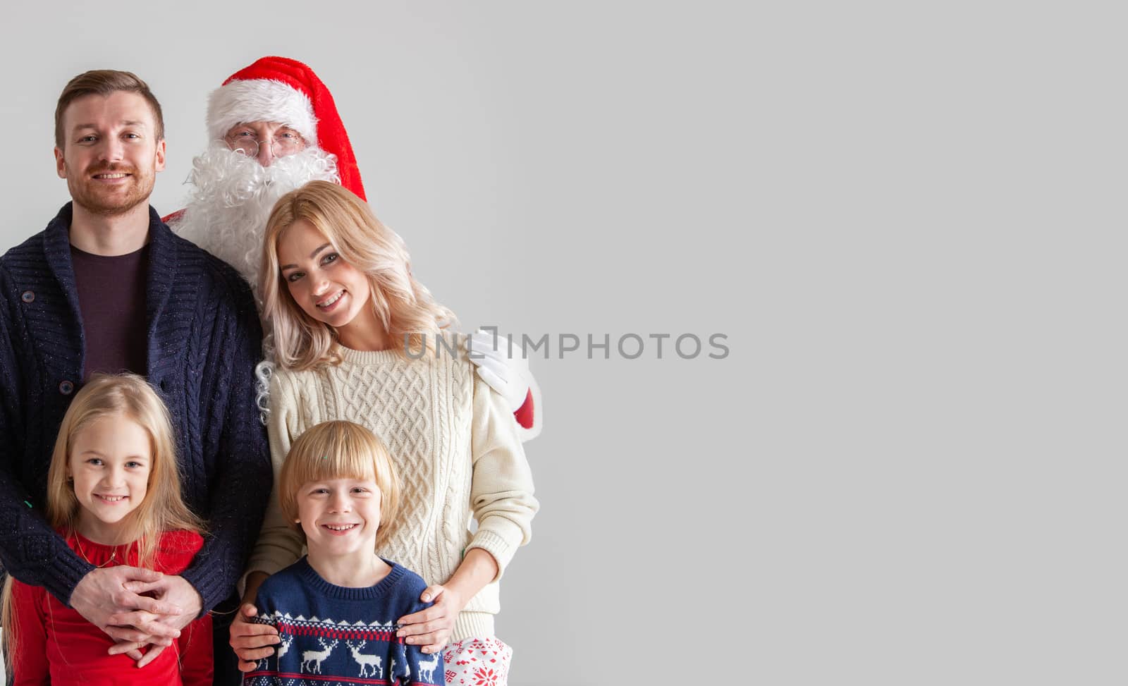 Portrait of young family with two children with Santa Claus, gray background with copy space for text