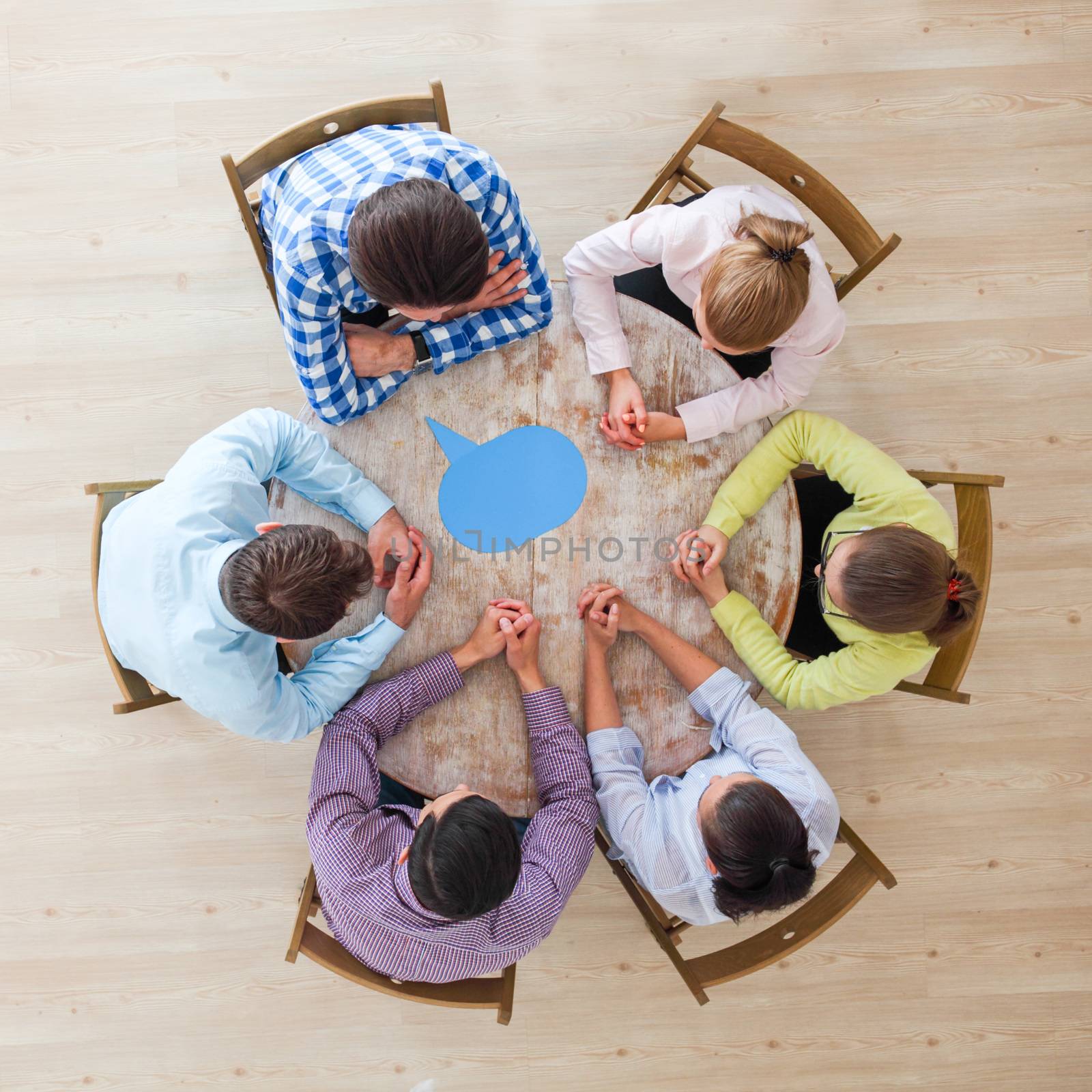 Team of business people in casual clothes sitting around the table with paper dialog boxes, discussing opinion concept