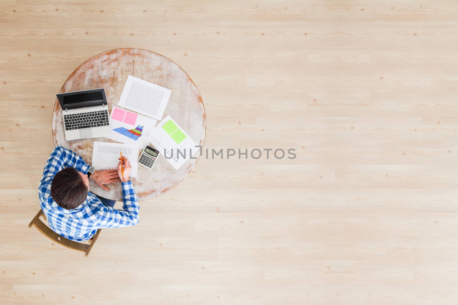 Businessman working with finance documents at office with laptop, and graph data papers on his desk, top view with copy space