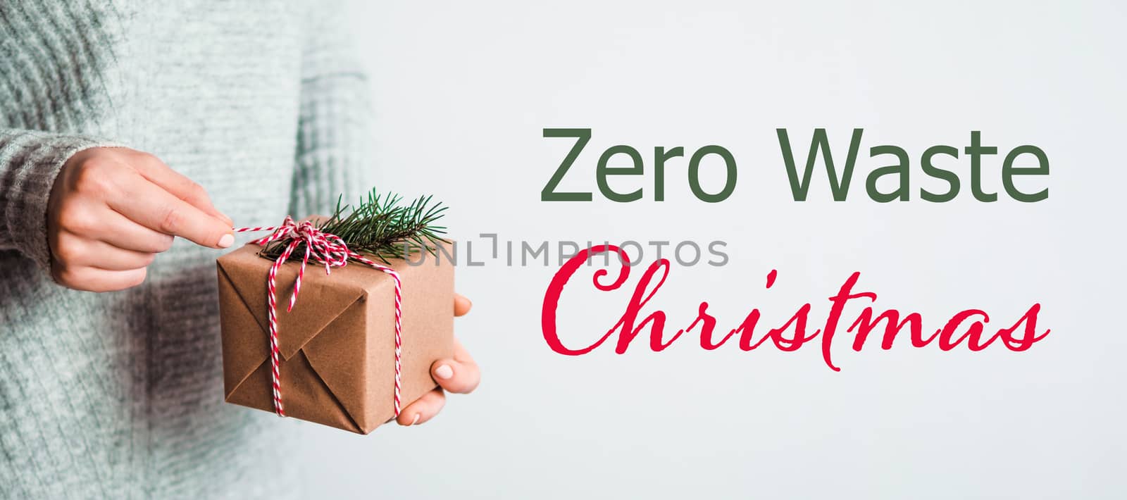 Zero waste Christmas concept. Female hands opening gift box in craft wrapping paper. Free font letters Zero Waste Christmas.