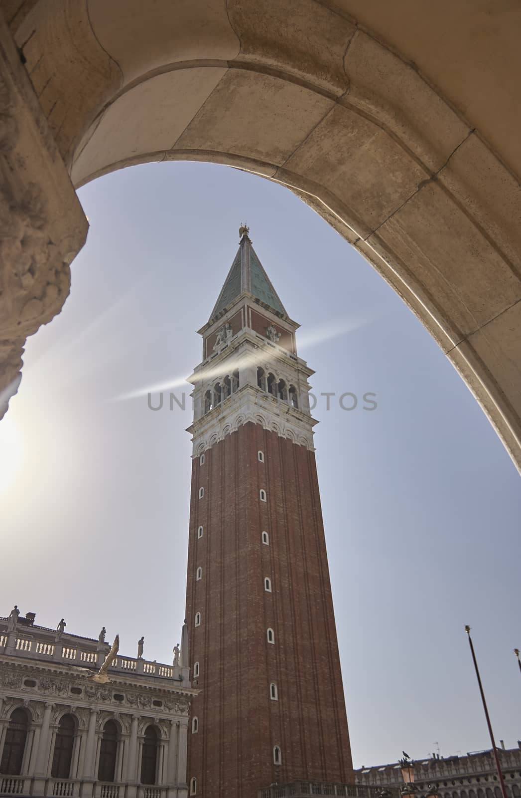 The tip and central part of the bell tower of the San Marco Basilica in Venice seen from below one of the porticoes in the piazza san marco where the bell tower itself is. Vertical Shoot.