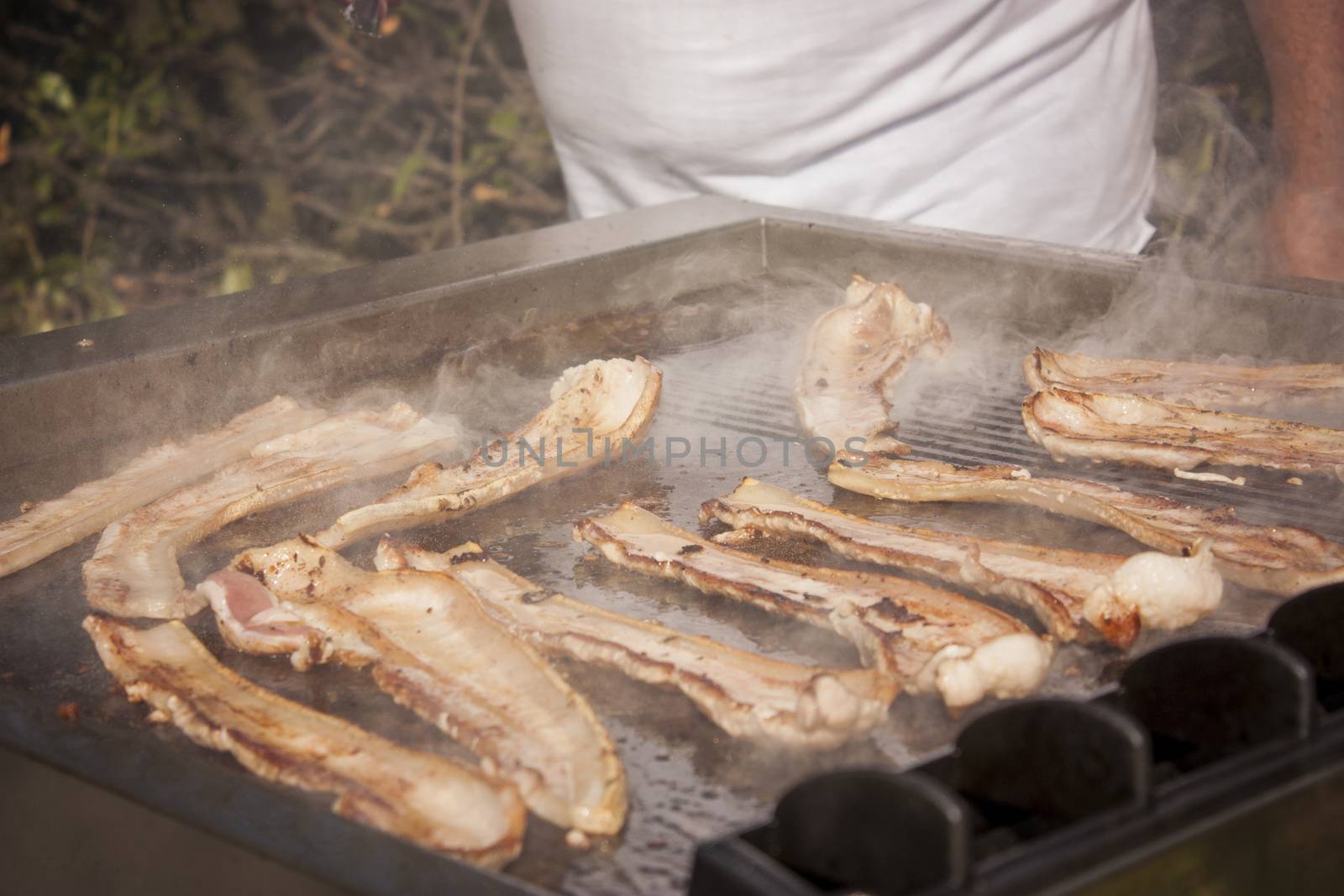 Crunchy bacon on the grill during preparation while cooking and roasting for lunch.