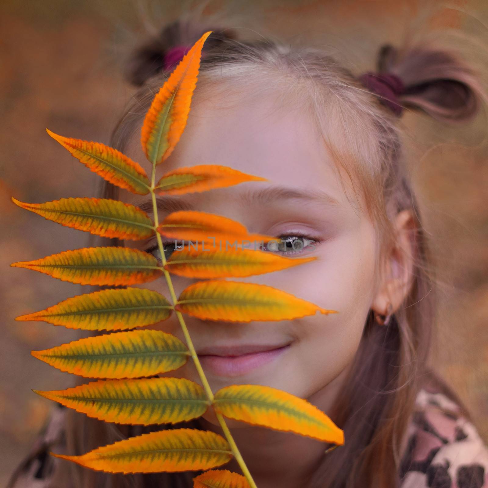 Girl holding colorful leaf in autumn park.