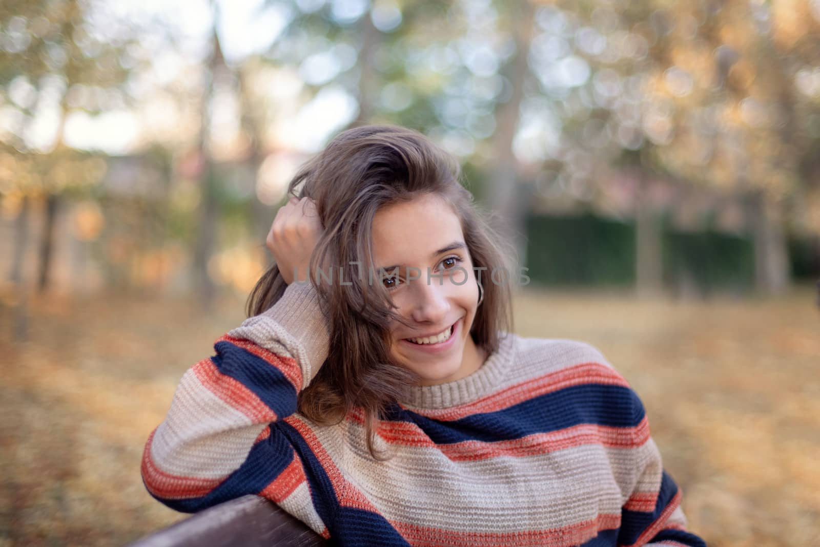 A beautiful girl smiles while sitting on a bench in the autumn.A girl sits on a bench and admires the autumn.