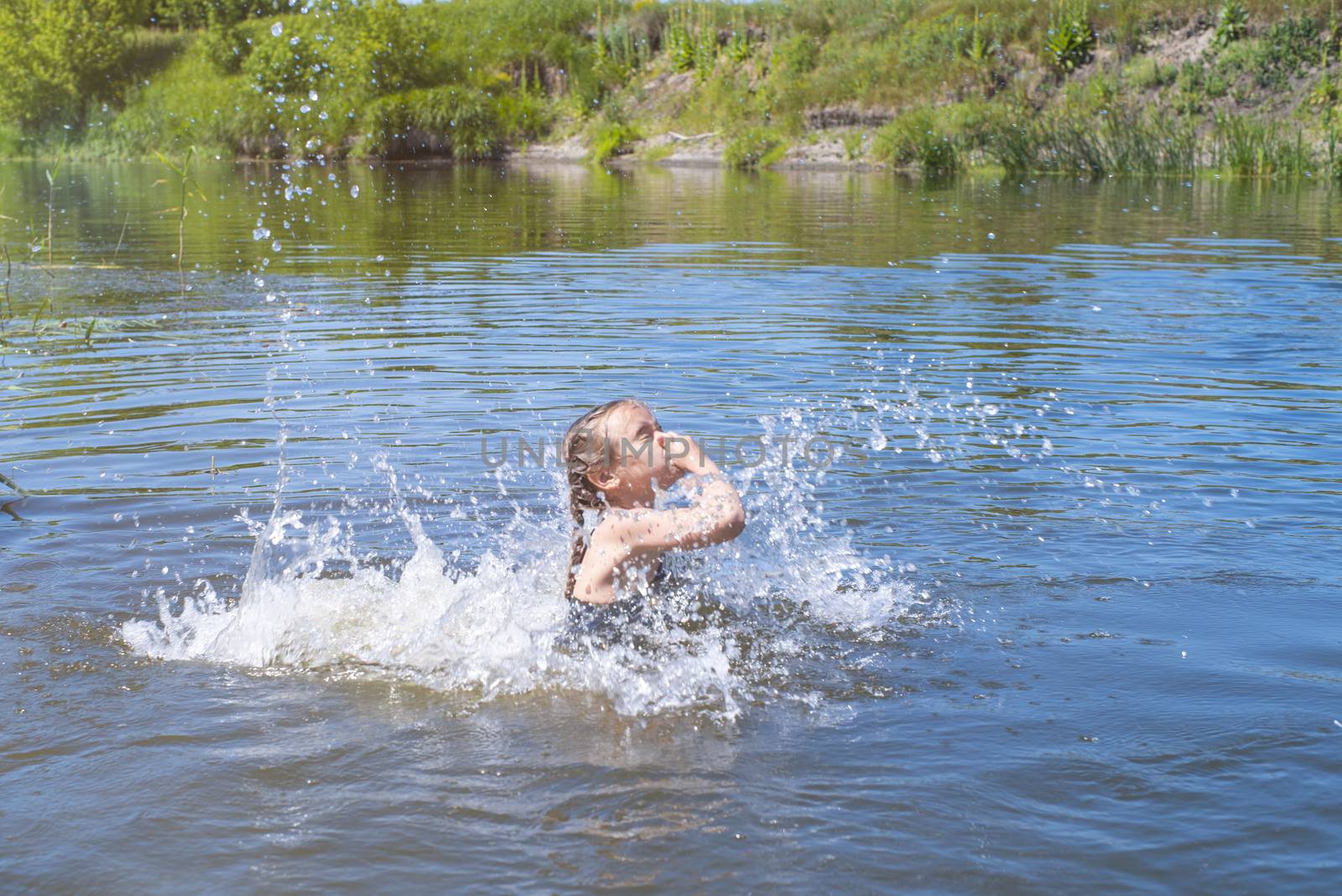 little girl running through the water with a splash . in her hands cloth.