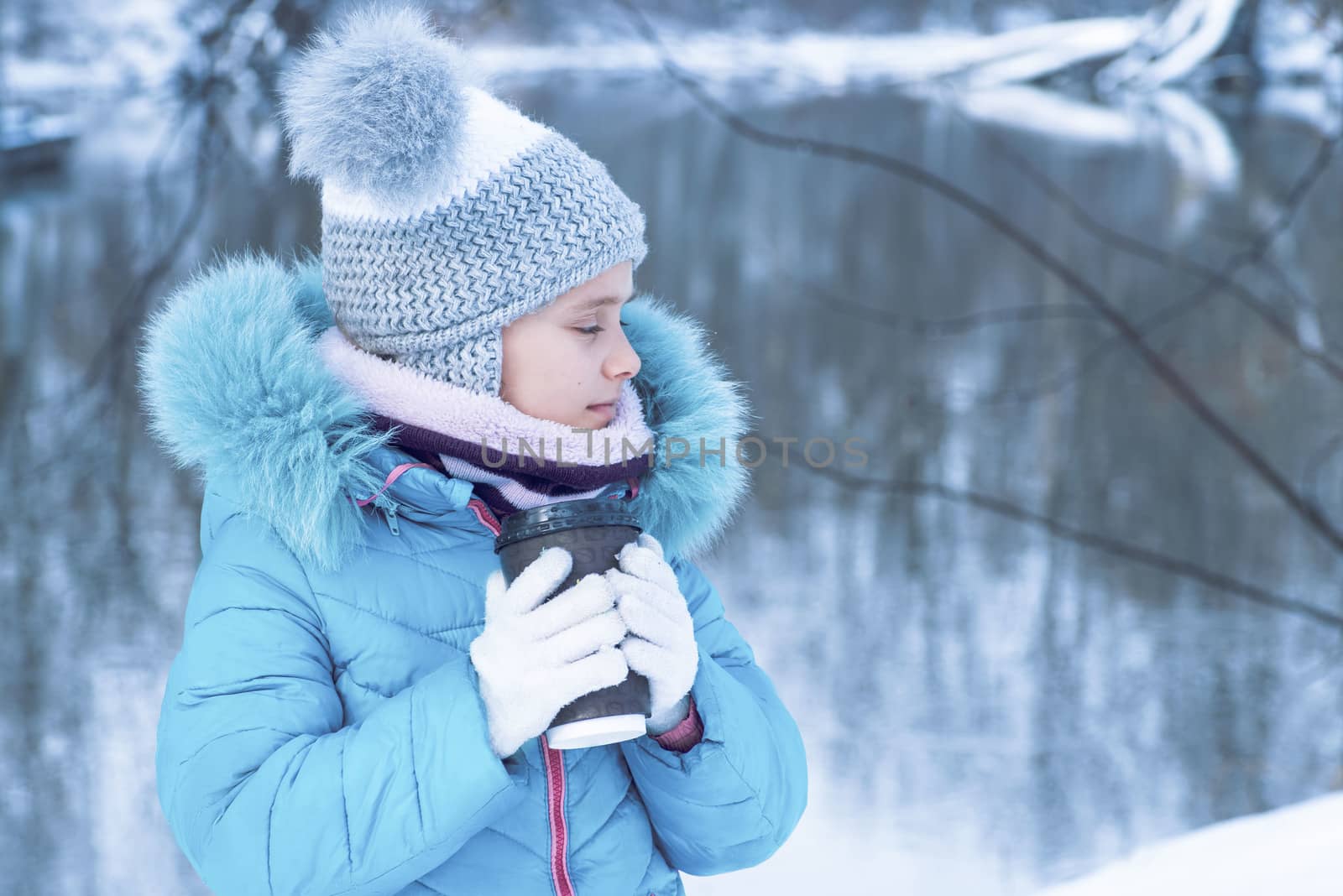 Winter season, portrait of a cute girl with a cup of hot tea outdoors