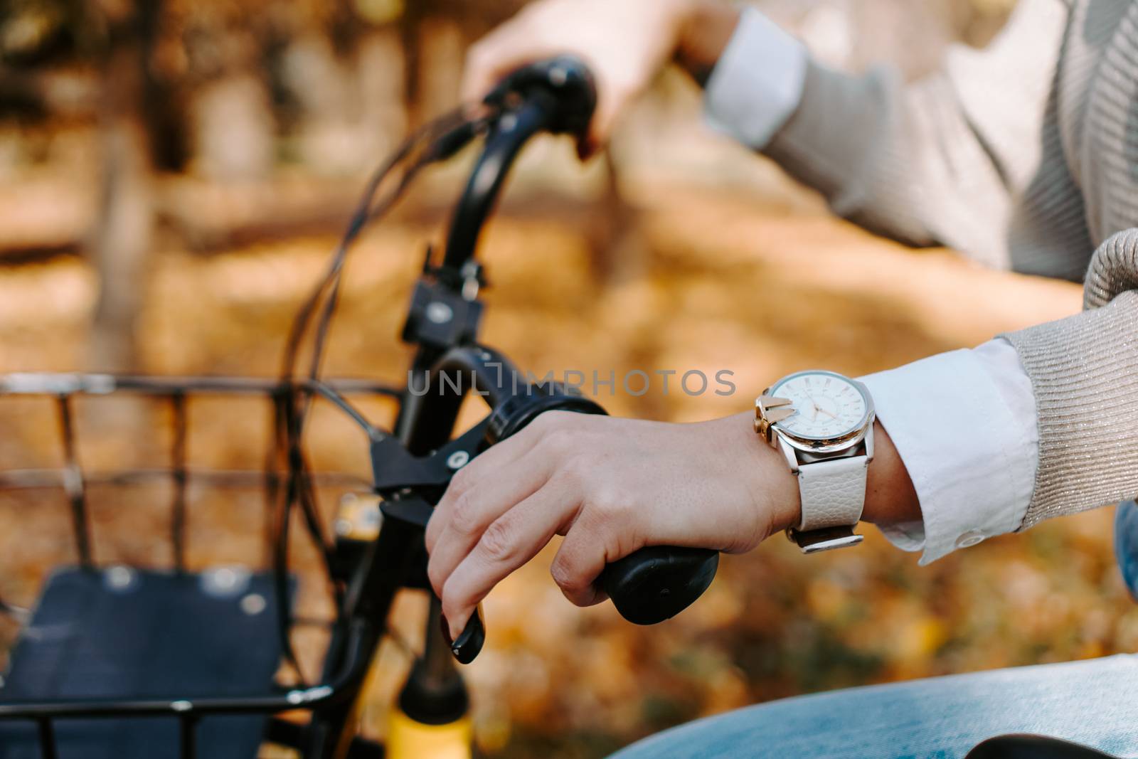 Riding a bike on a sunny day in autumn park. Female hand on a bicycle wheel