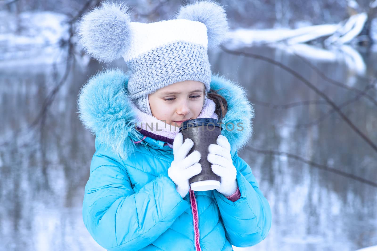 Winter season, portrait of a cute girl with a cup of hot tea outdoors