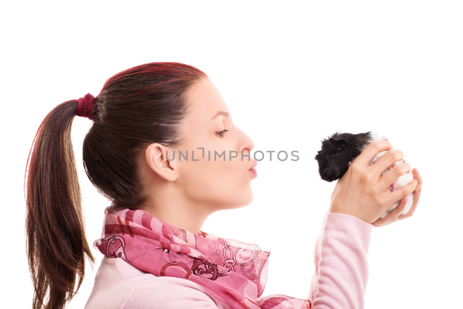A portrait of a beautiful young girl giving a kiss to her cute pet guinea pig, isolated on white background.