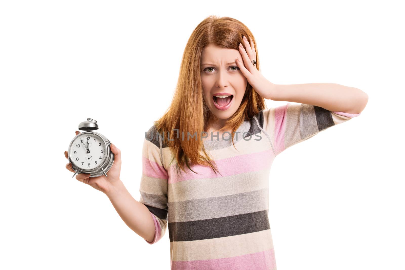 Being late concept. A portrait of a young woman holding an alarm clock, panicking about being late, isolated on white background.