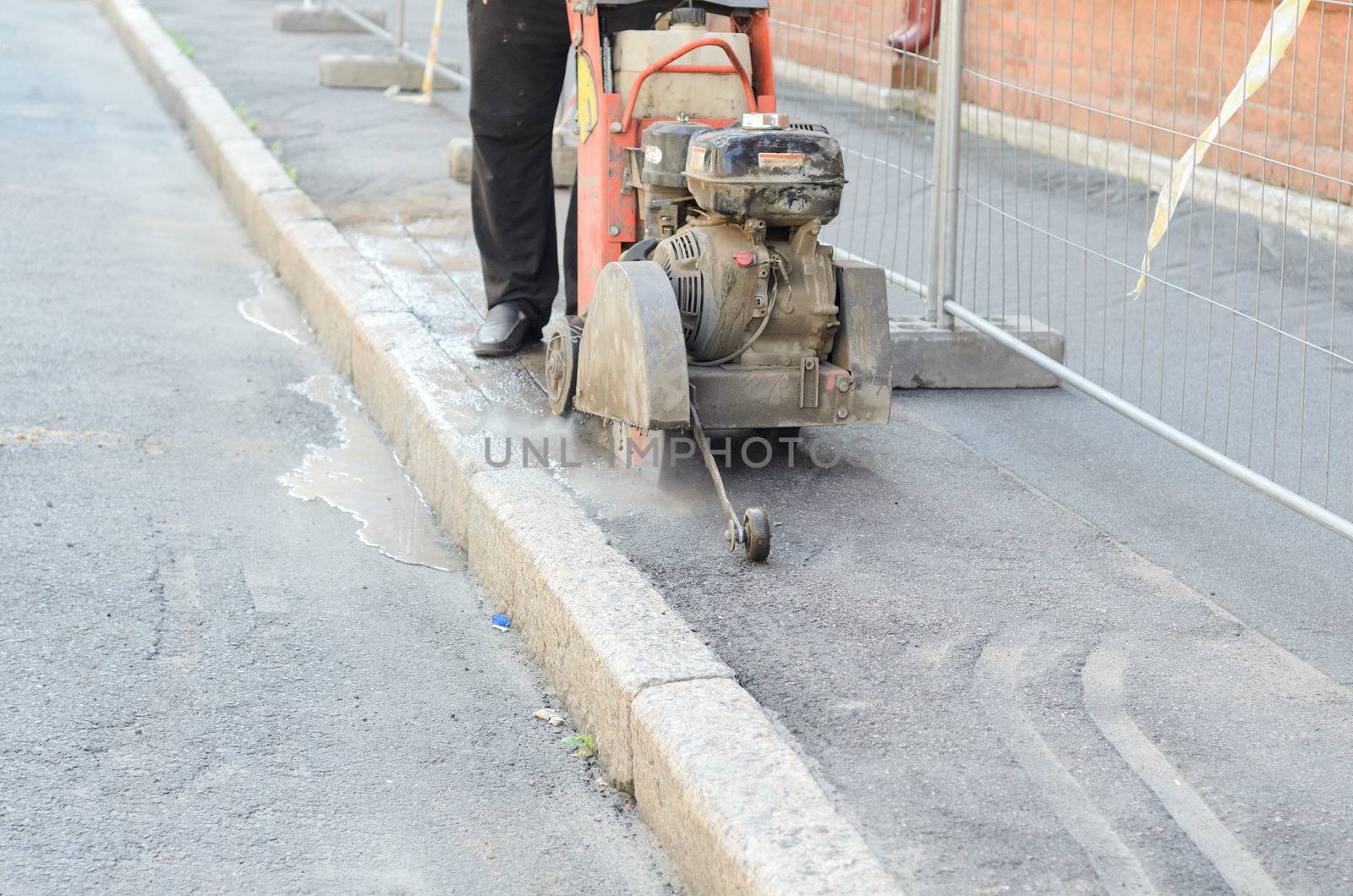 Road worker cutting asphalt road, working on the road reconstruction. by andre_dechapelle